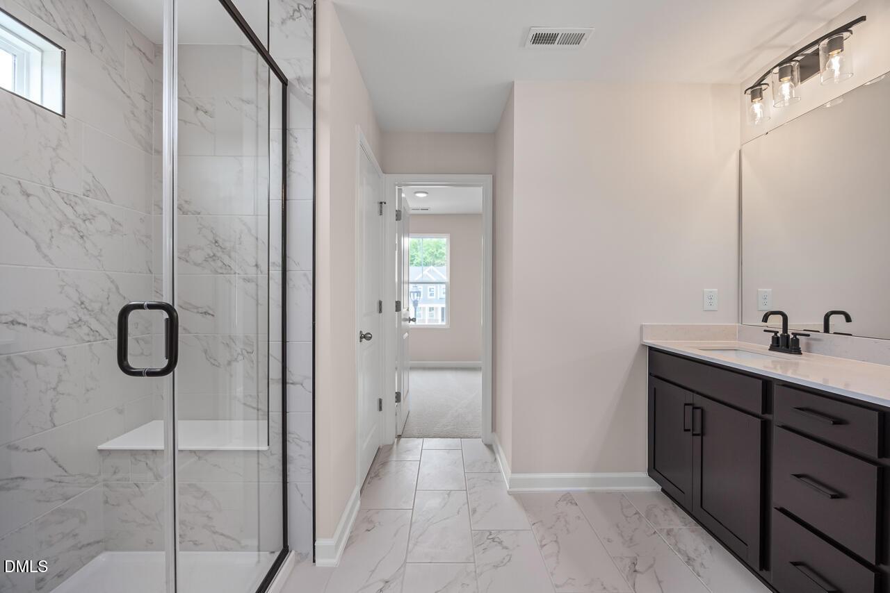 Modern bathroom with marble-style walk-in shower and dark vanity in The Willow B floor plan, Woodland Crossing, Zebulon, NC.