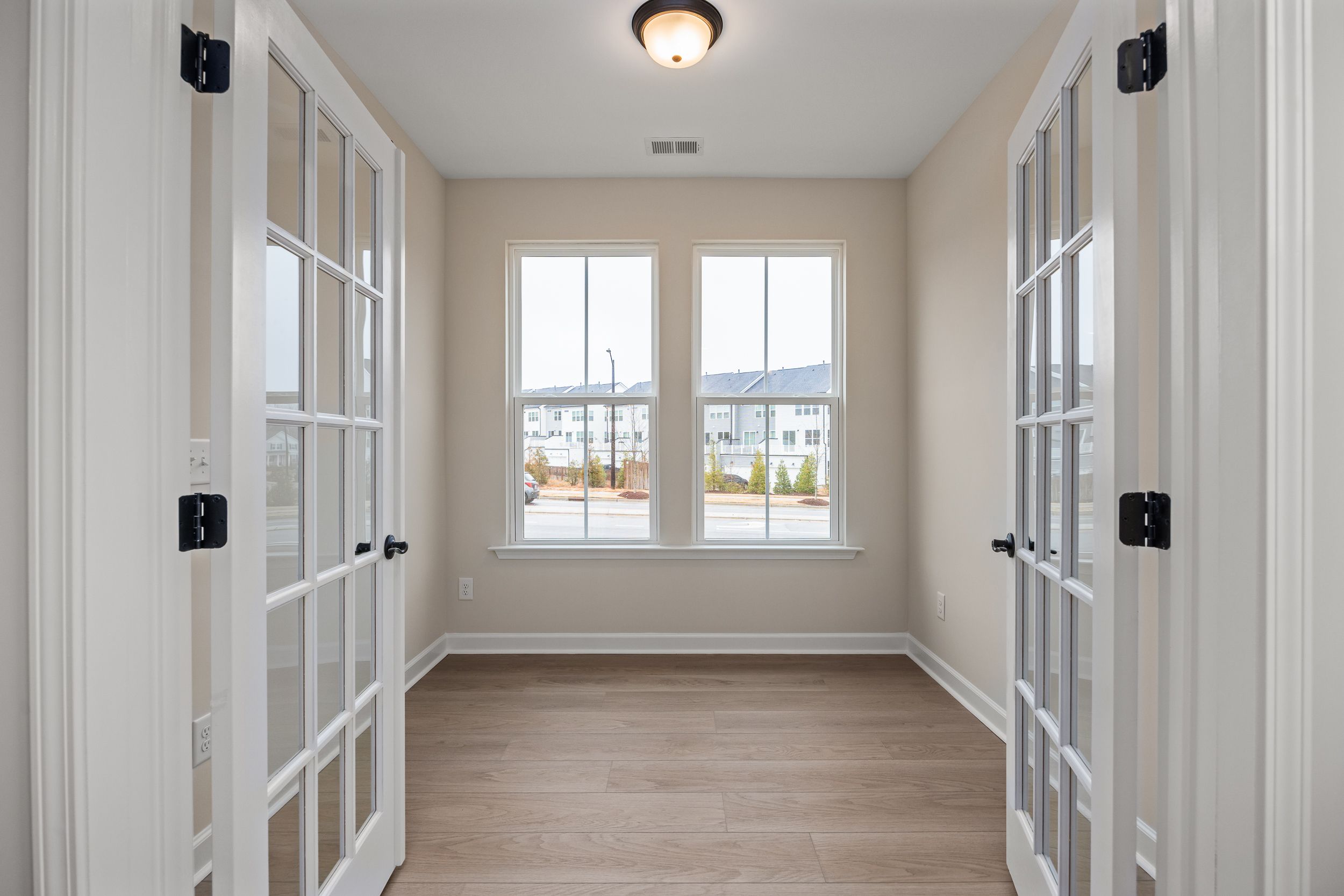 Sunroom with French doors, large windows, and hardwood floors at Forestville Yard in Knightdale NC offering community views
