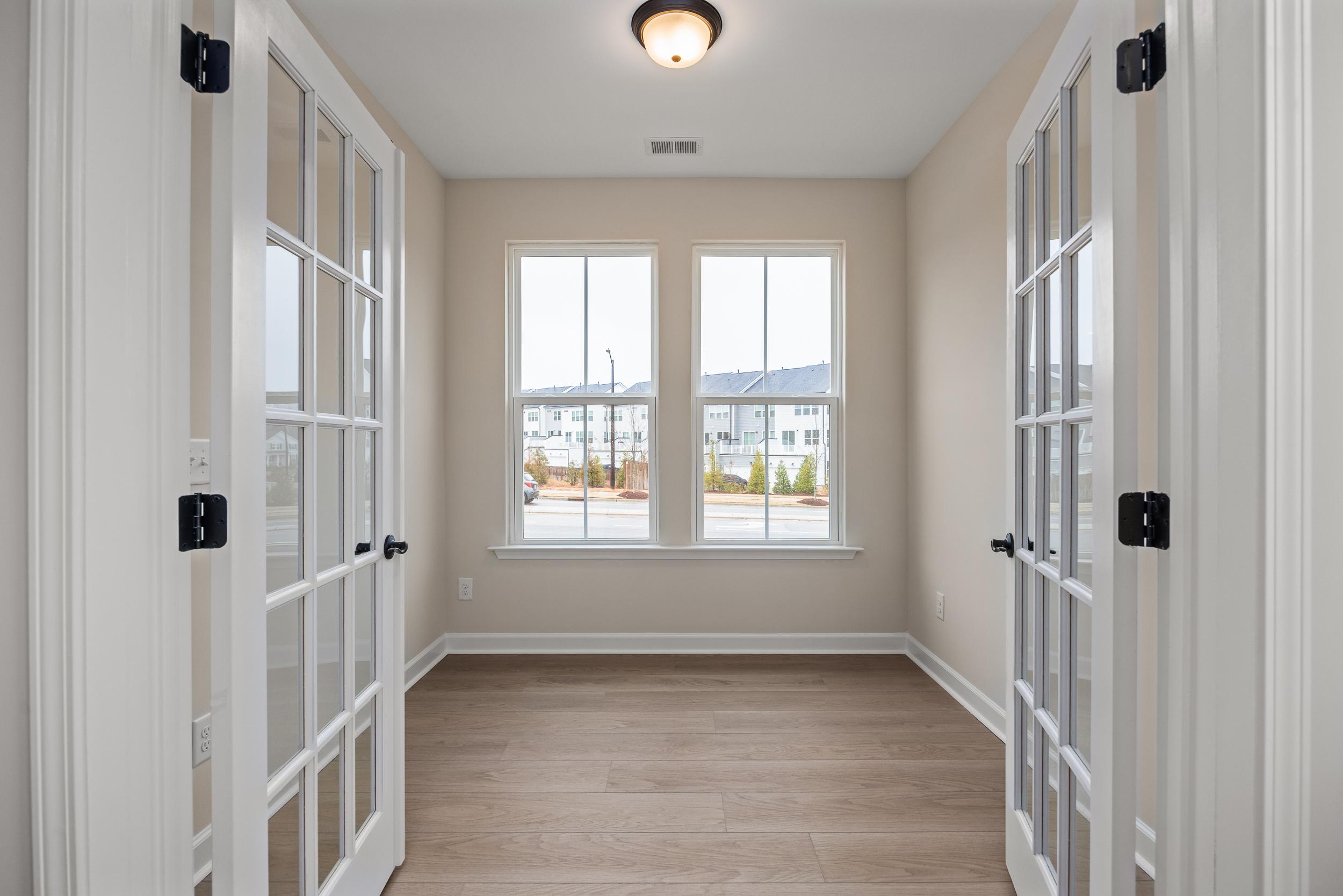 Sunroom with French doors, large windows, and hardwood floors at Forestville Yard in Knightdale NC offering community views