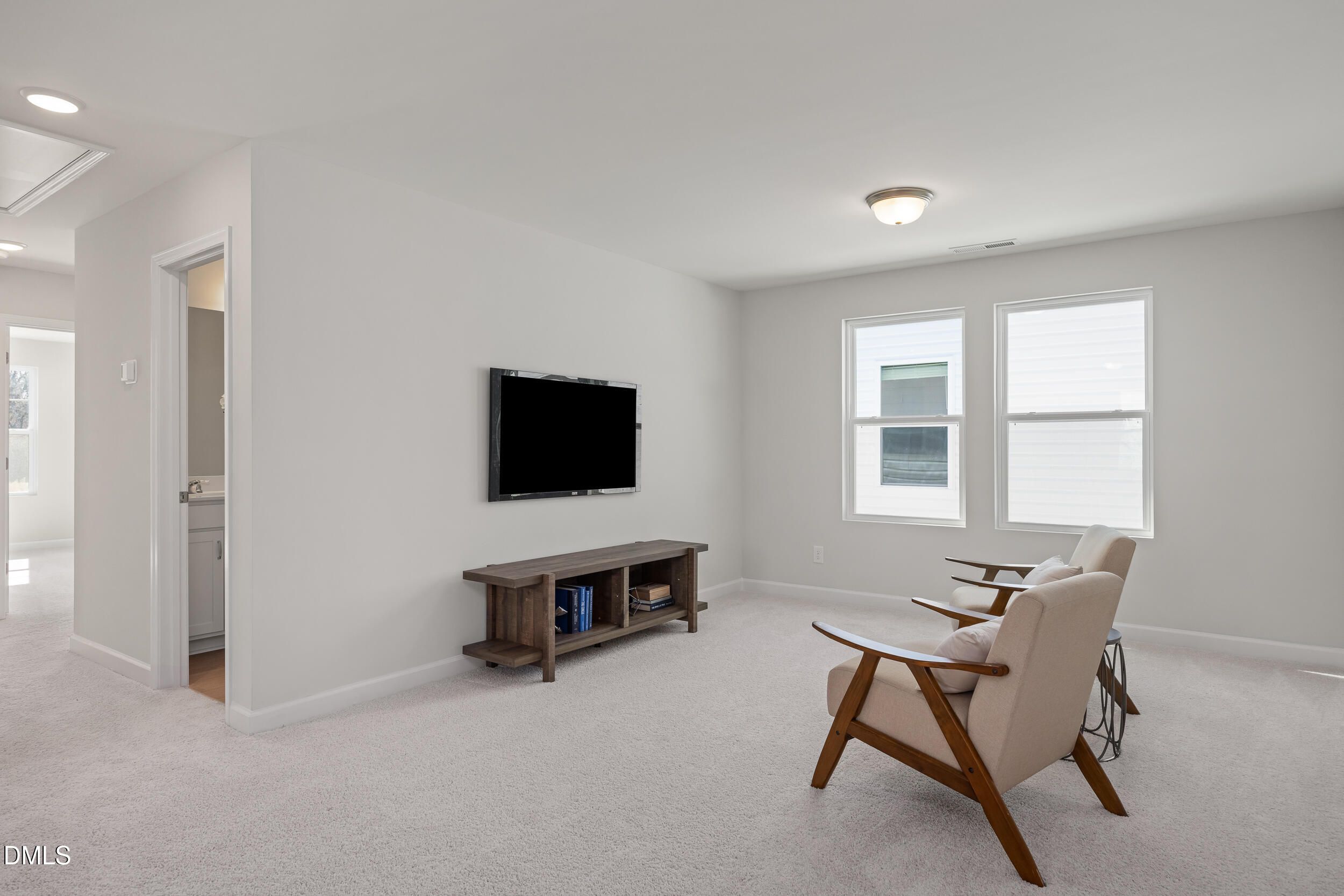 Cozy upstairs loft with wall-mounted TV, wooden media console, armchairs, and large windows in Davidson Homes The Preston C, Lillington, NC