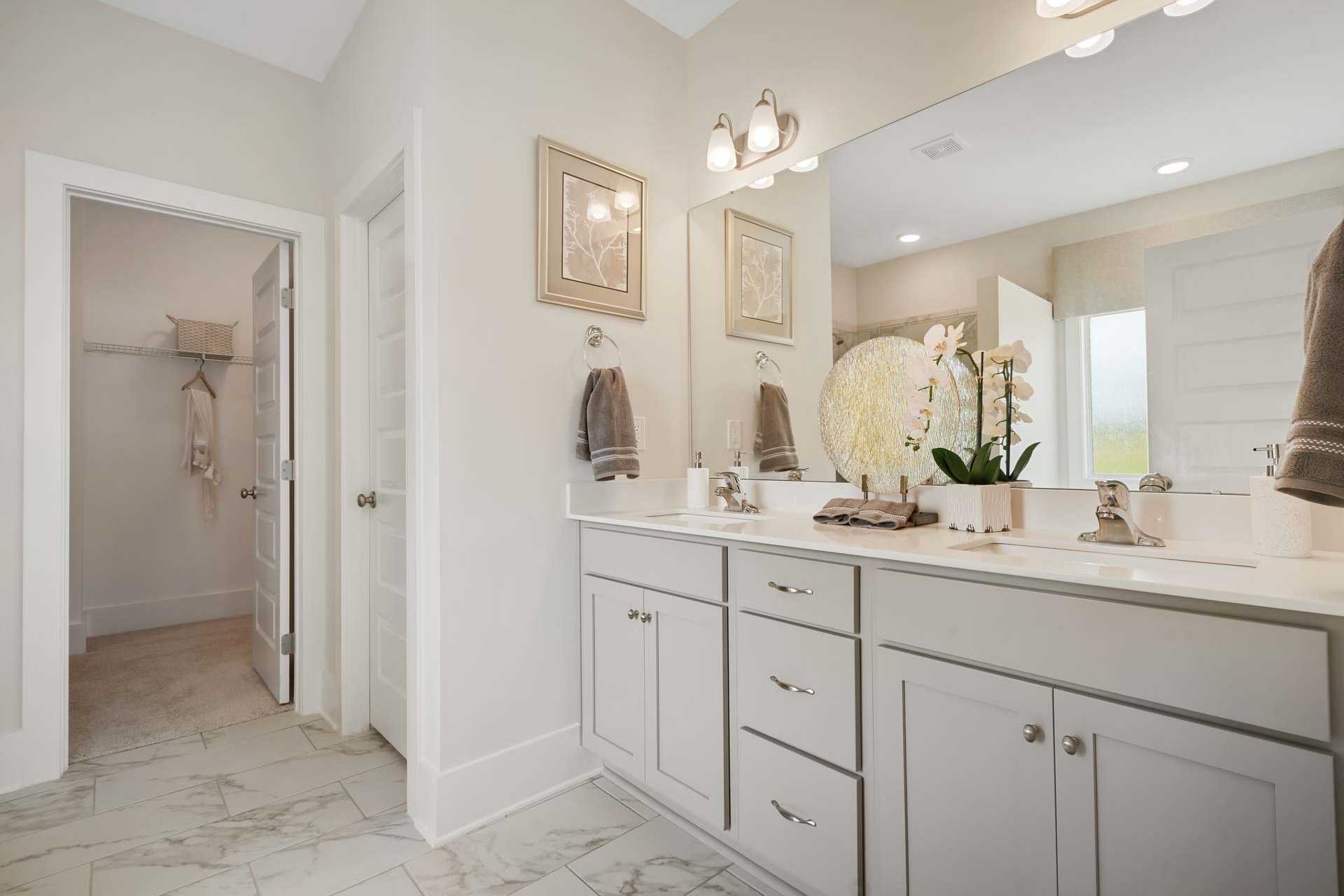 Spacious primary bathroom at Flint Meadows in New Market, Alabama with double vanity, orchids, and walk-in closet