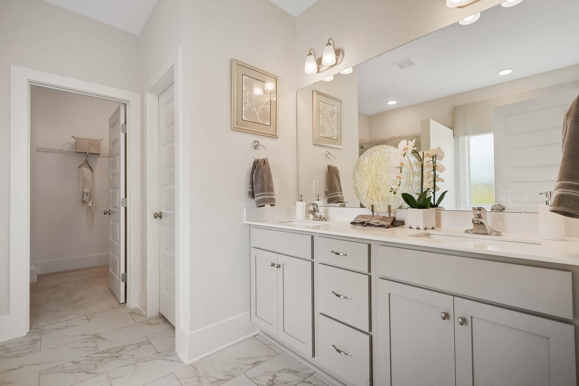 Spacious primary bathroom at Flint Meadows in New Market, Alabama with double vanity, orchids, and walk-in closet