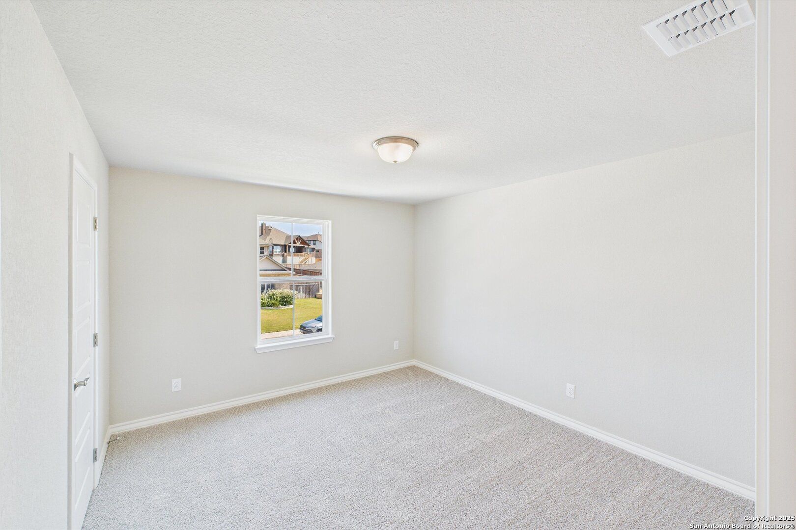 Bright empty bedroom with beige carpet, neutral walls, and window overlooking yard in Davidson Homes The Jennings H, Ladera San Antonio