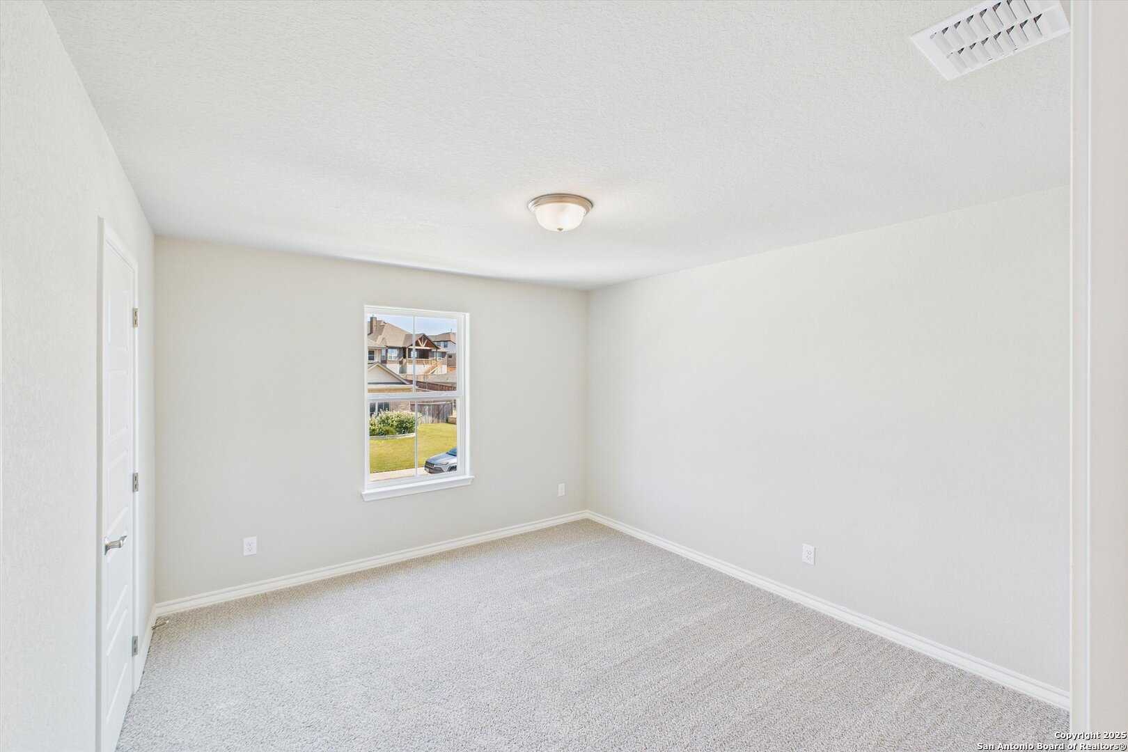 Bright empty bedroom with beige carpet, neutral walls, and window overlooking yard in Davidson Homes The Jennings H, Ladera San Antonio