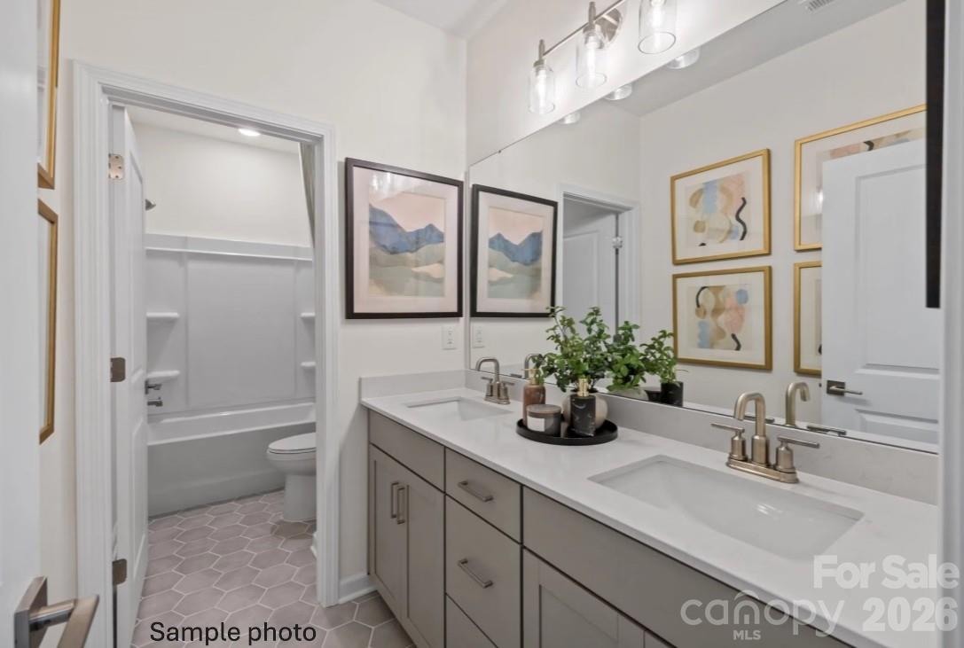 Modern bathroom with dual vanity, white countertops, and gray cabinets in The Beech B floor plan at Enclave at Belmont.