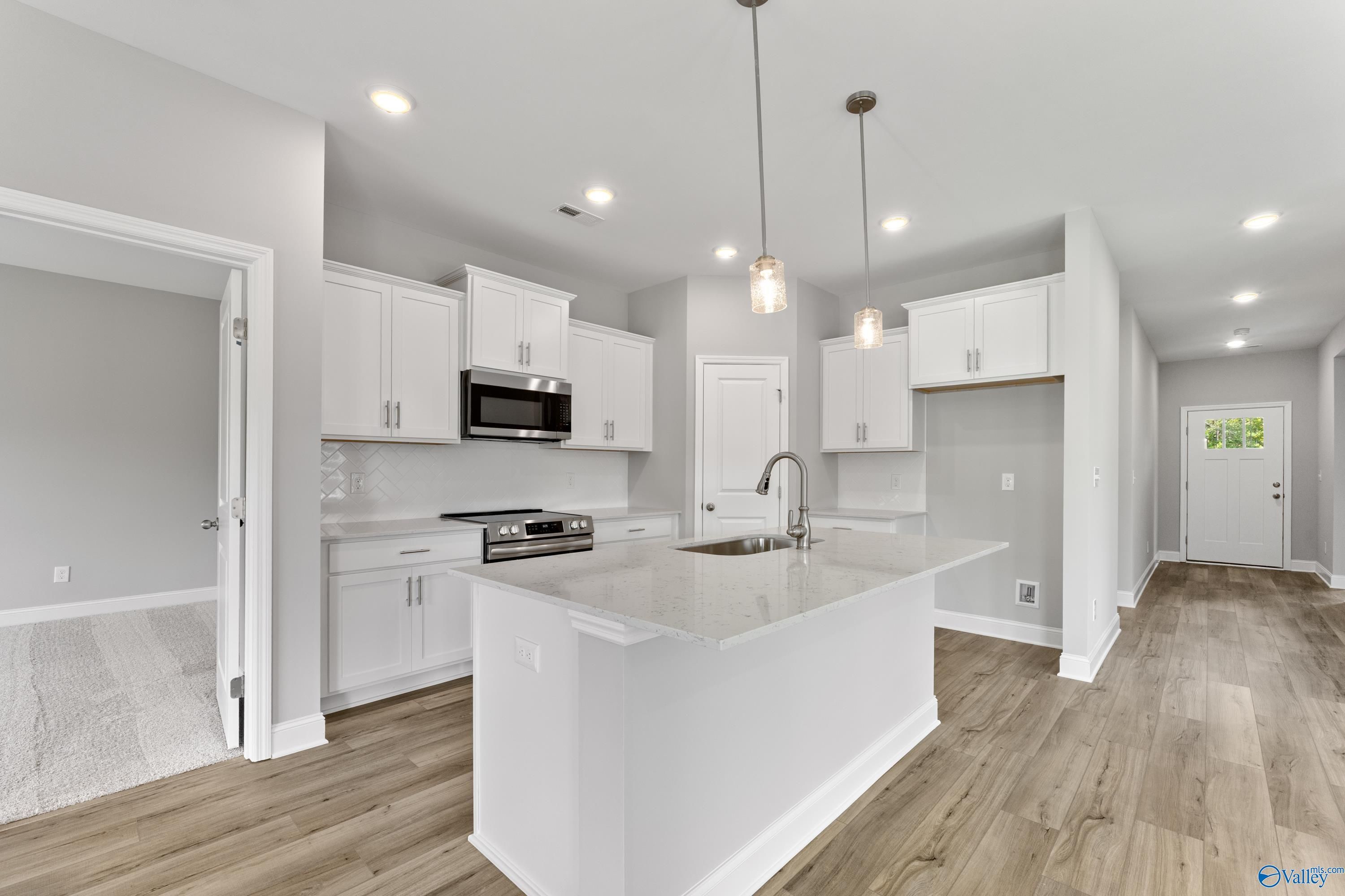 Modern white kitchen with quartz island, stainless appliances, and open layout in Davidson Homes Franklin C, Huntsville AL