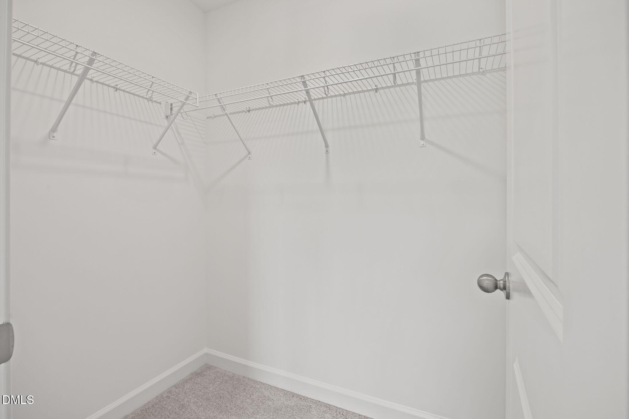 Spacious walk-in closet with white wire shelving and hanging rods in The Willow D 4-bedroom home, Wendell Ridge, NC