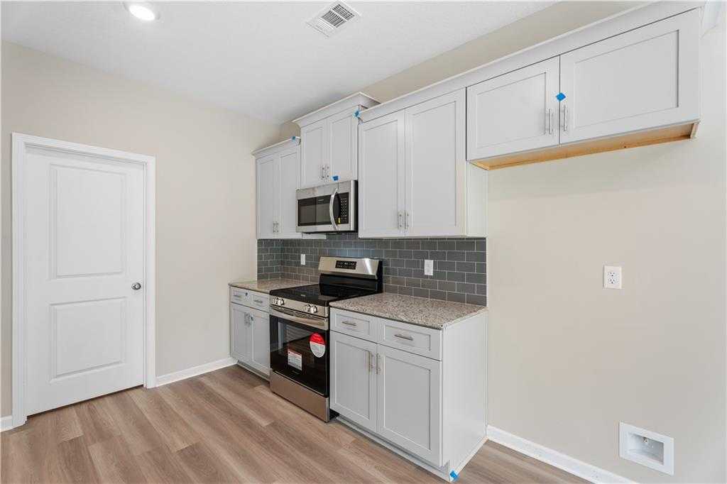 Modern kitchen with white shaker cabinets, stainless steel appliances, granite counters, subway tile backsplash in Davidson Homes The Bartlett, Phenix City, Alabama