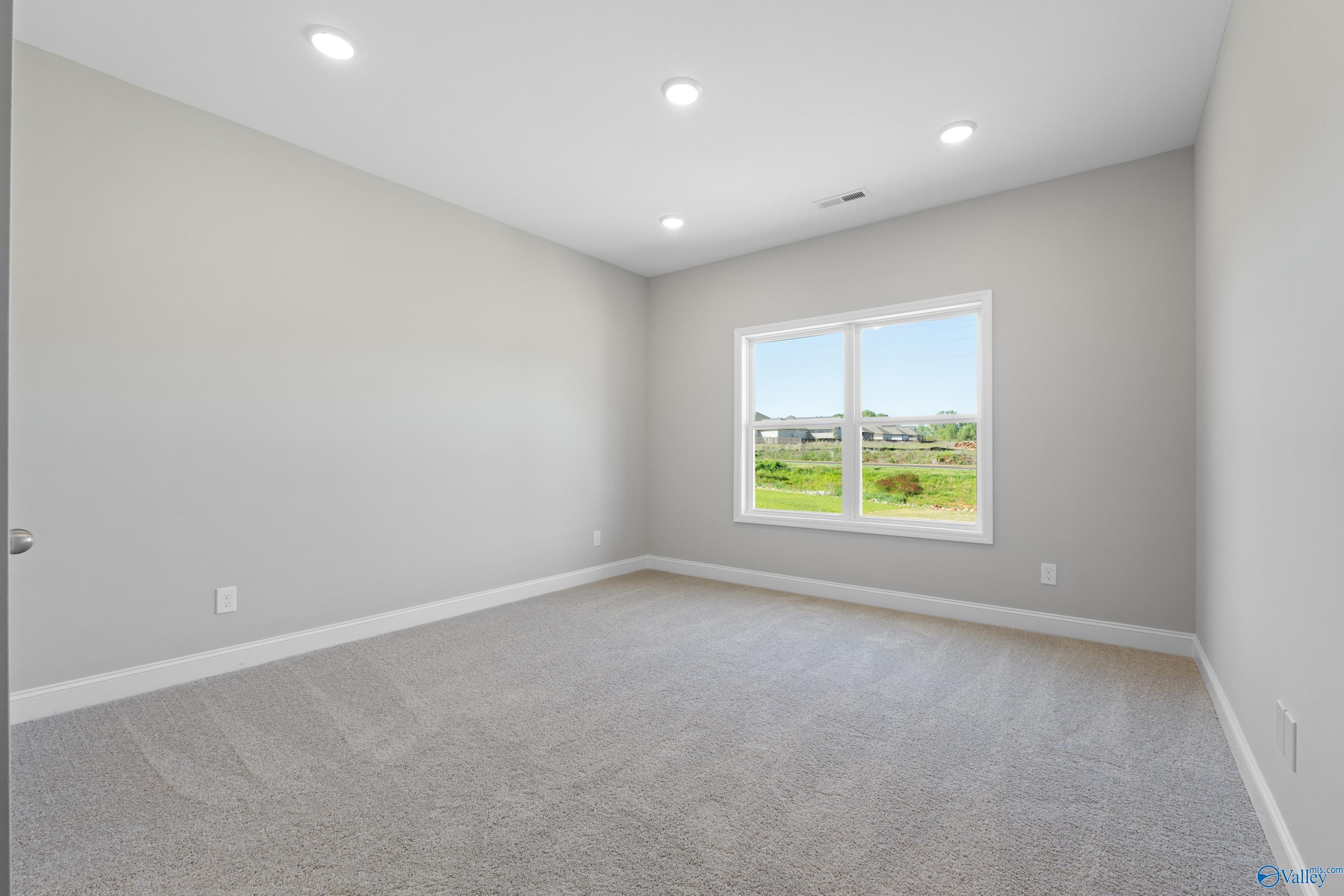 Bright secondary bedroom with gray walls, carpet floor, and large window view of green fields in Davidson Homes The Asheville C, Athens, Alabama