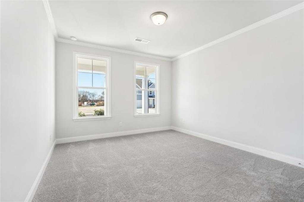 Bright secondary bedroom with white walls, gray carpet, and large windows overlooking yard in Davidson Homes The Hickory C, Hoschton, Georgia