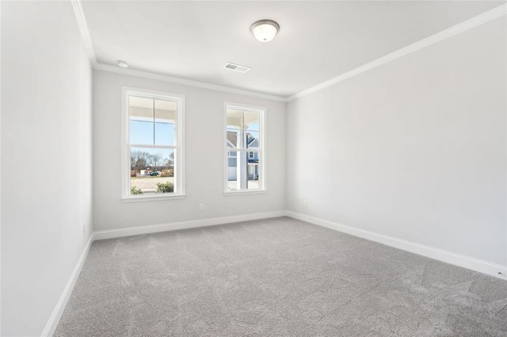 Bright secondary bedroom with white walls, gray carpet, and large windows overlooking yard in Davidson Homes The Hickory C, Hoschton, Georgia