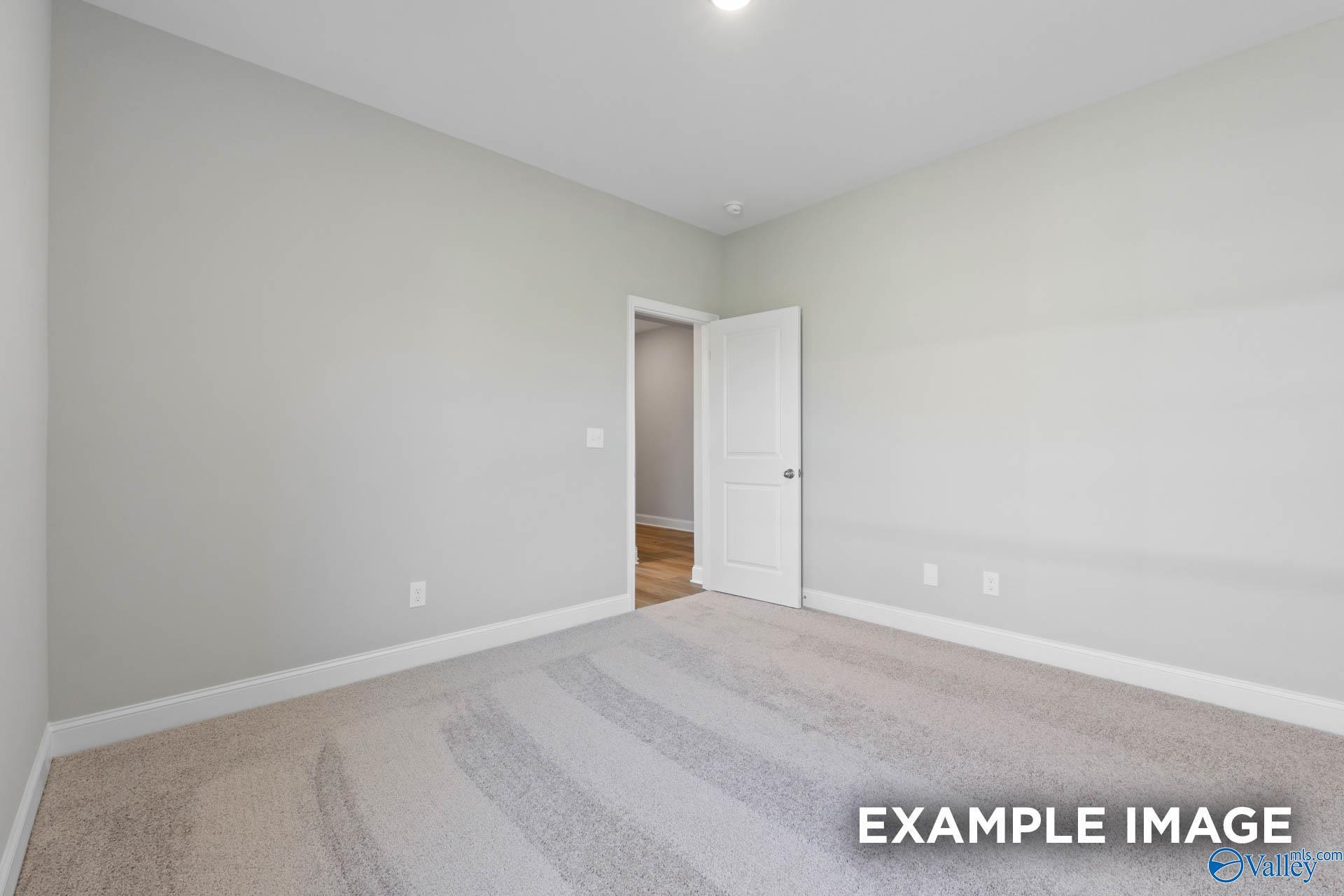 Secondary bedroom featuring light gray walls, beige carpet, and open door to tiled bathroom in Davidson Homes The Everett B, Hazel Green, Alabama