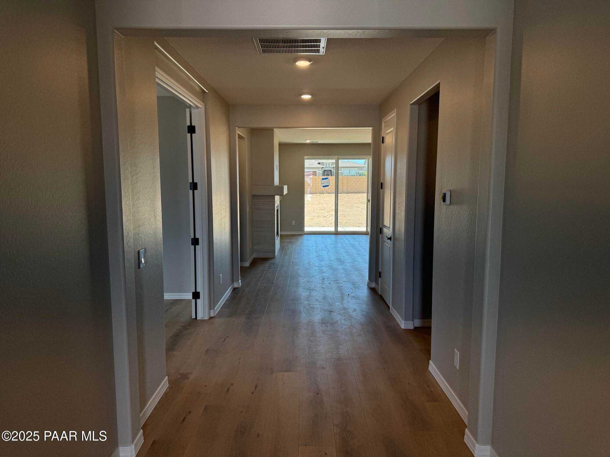 Spacious hallway with hardwood floors, bedroom doors, and desert-view windows in Davidson Homes Sheridan II B, Prescott, AZ