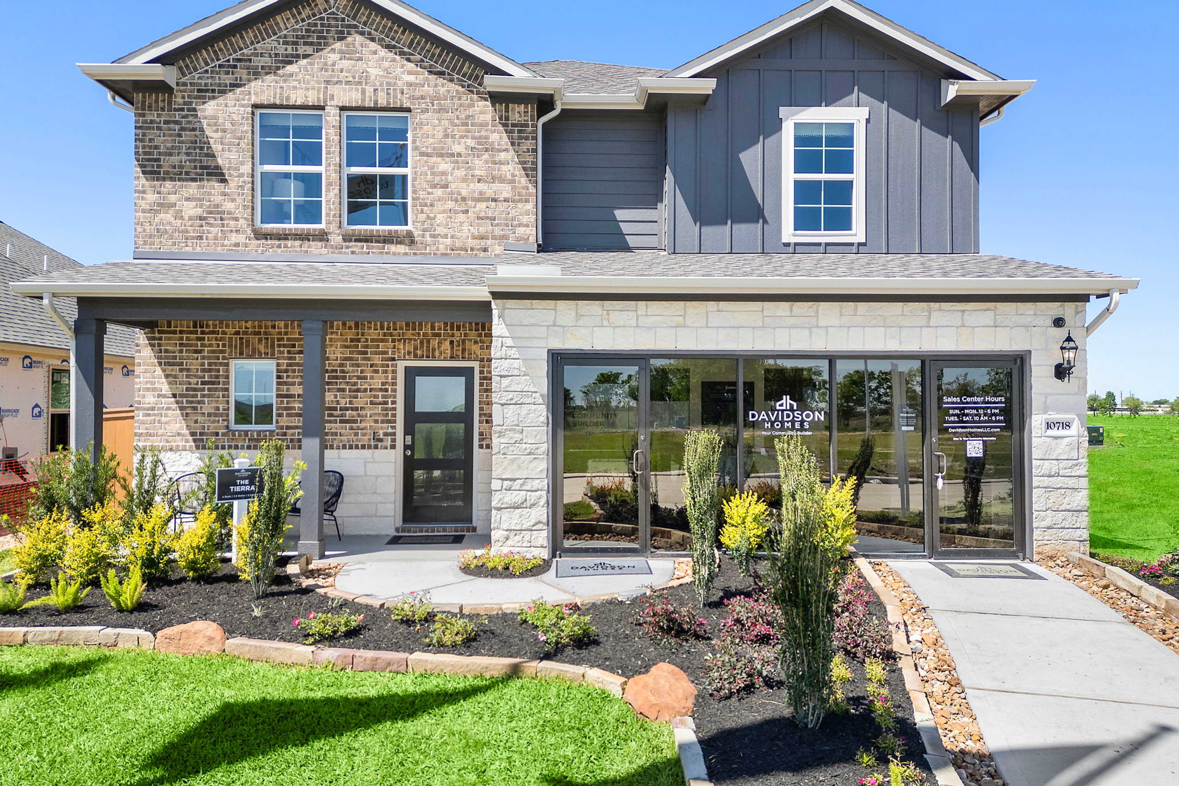 Modern two-story home exterior at Emberly in Beasley Texas by Davidson Homes with brick and gray siding, covered porch, and landscaped entry