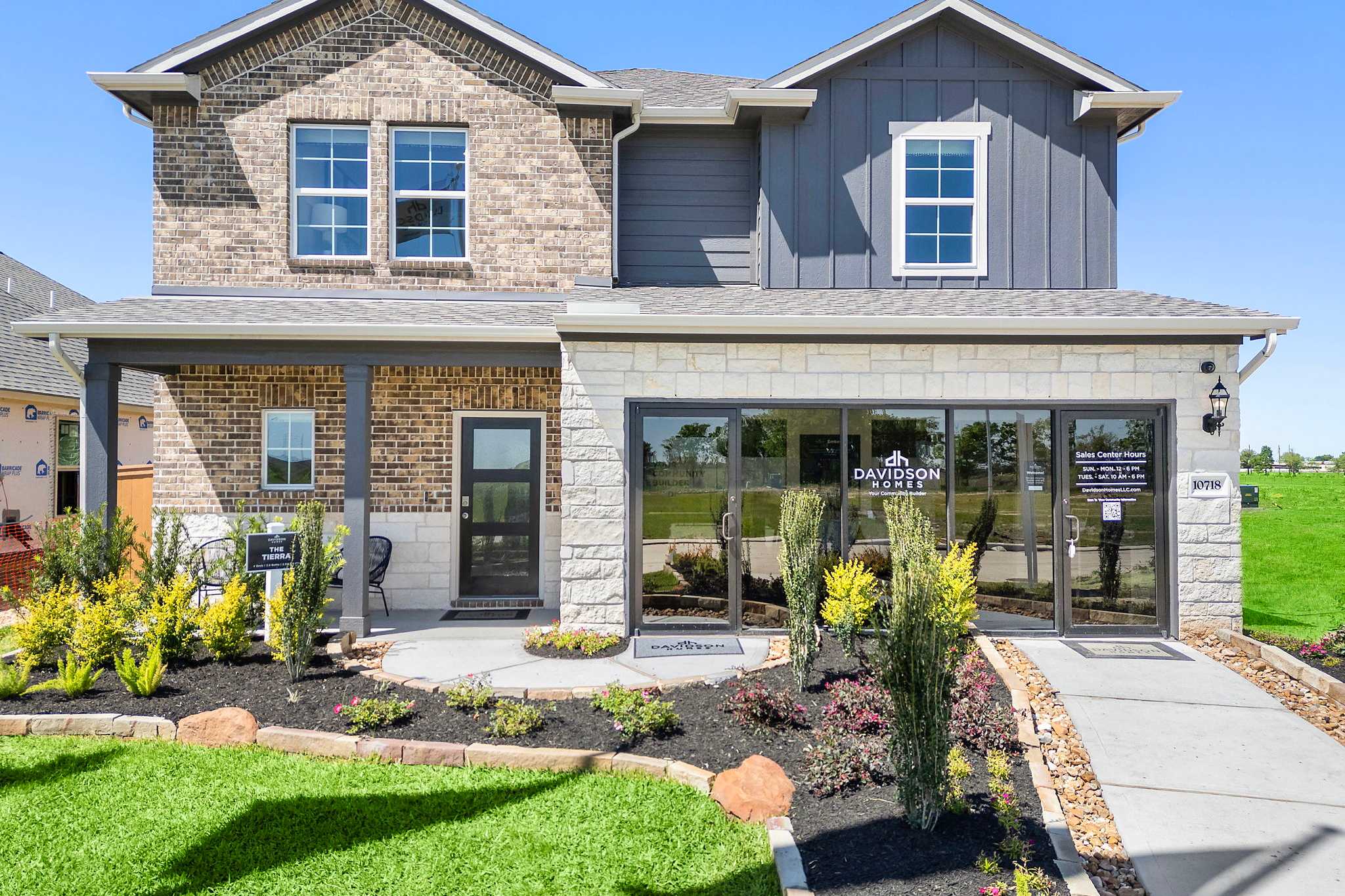 Modern two-story home exterior at Emberly in Beasley Texas by Davidson Homes with brick and gray siding, covered porch, and landscaped entry