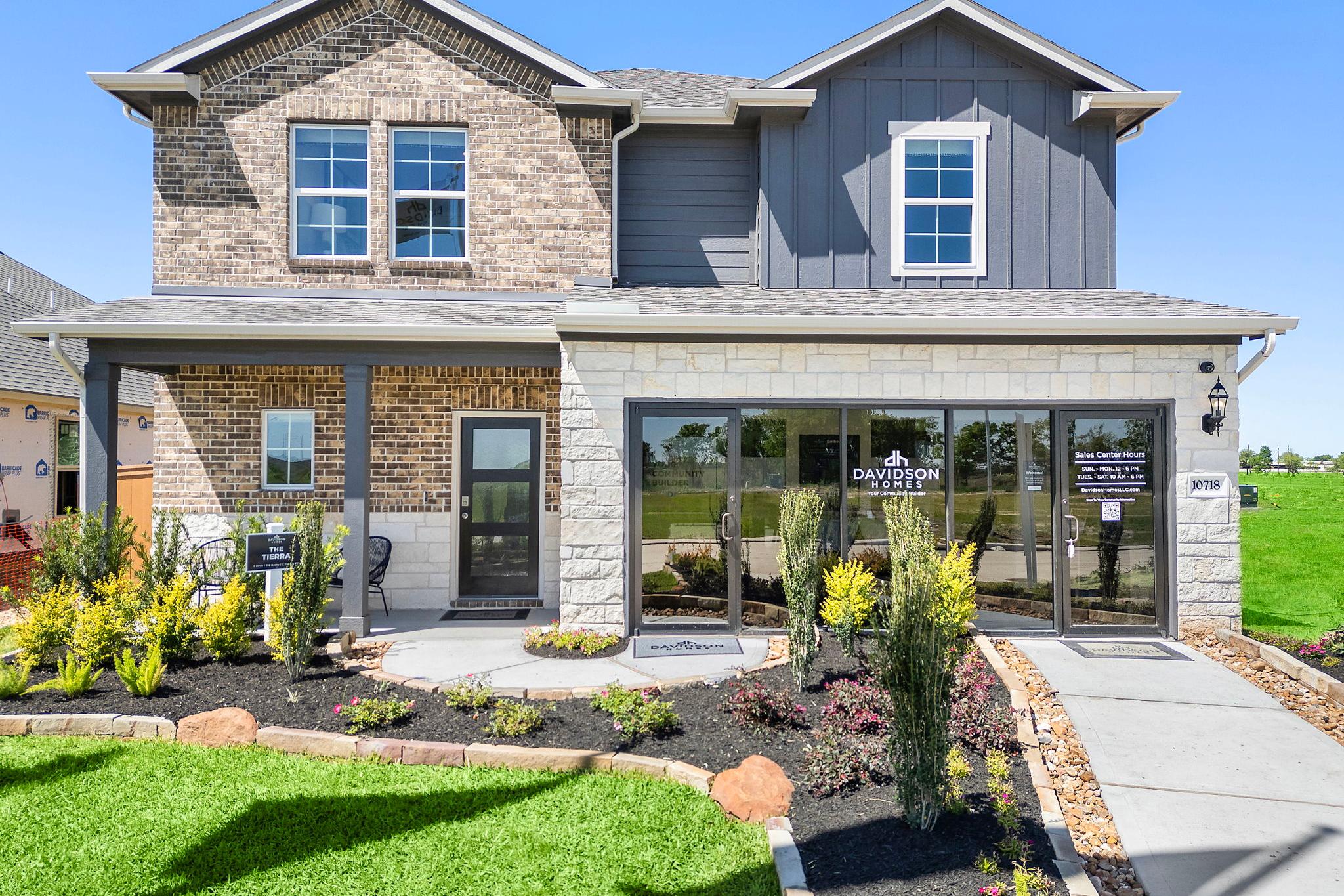 Modern two-story home exterior at Emberly in Beasley Texas by Davidson Homes with brick and gray siding, covered porch, and landscaped entry