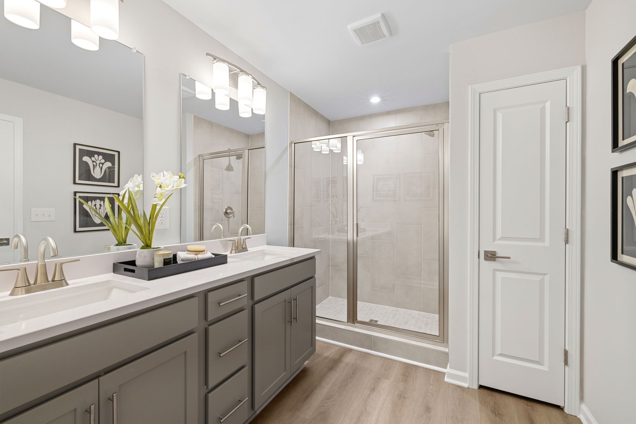 Modern primary bathroom at Lake Shore in Winder, Georgia with double vanity, glass shower, and hardwood floors