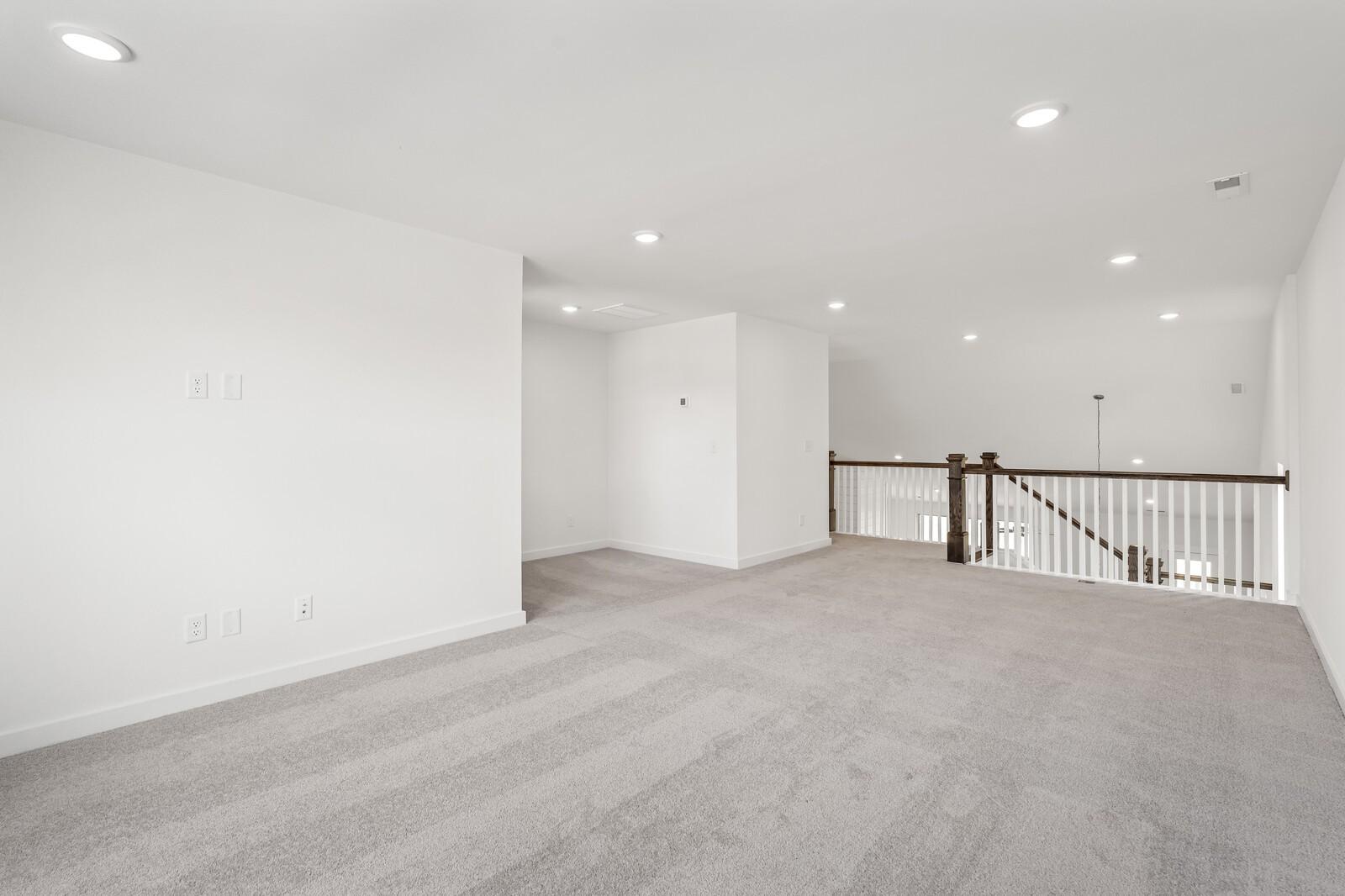 Spacious carpeted loft area with recessed lighting in The Ridgeport C floor plan at Woods Crossing, Gallatin, Tennessee.