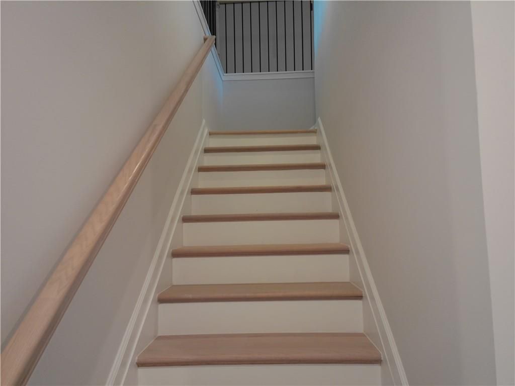 Elegant light oak staircase with wooden handrails and black metal railing in 2-story The Marion C home, Winder, Georgia