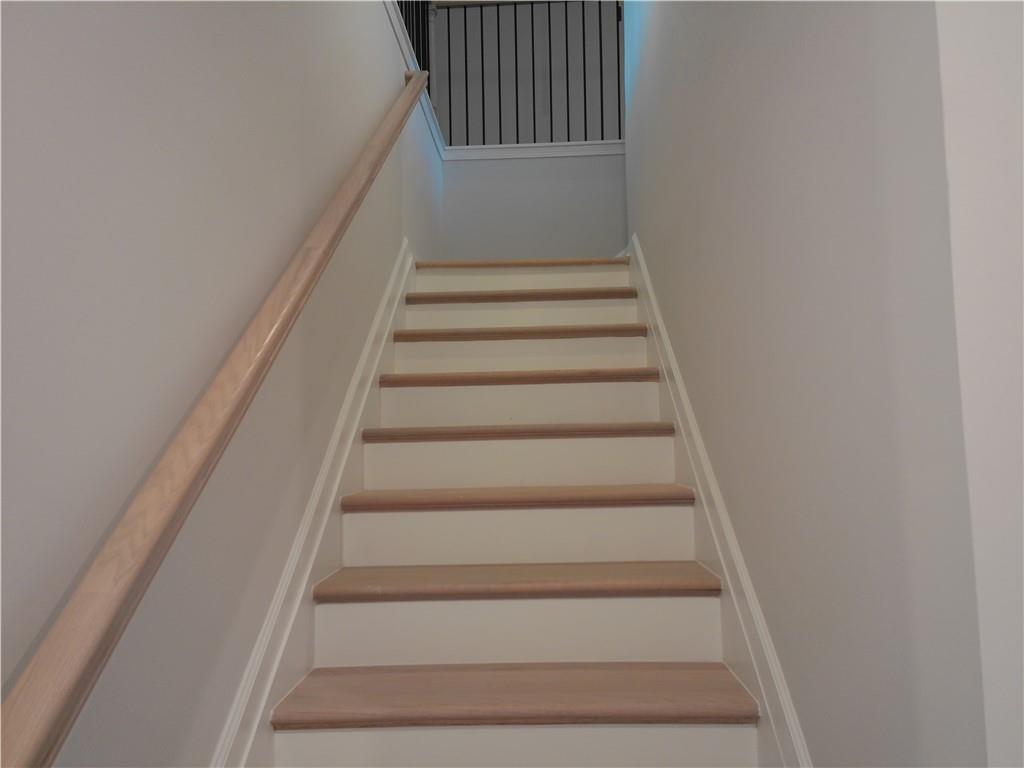 Elegant light oak staircase with wooden handrails and black metal railing in 2-story The Marion C home, Winder, Georgia