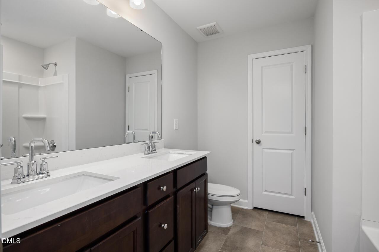 Modern bathroom with double vanity, dark cabinets, and shower in The Adalynn A floor plan at Gregory Village, Lillington.