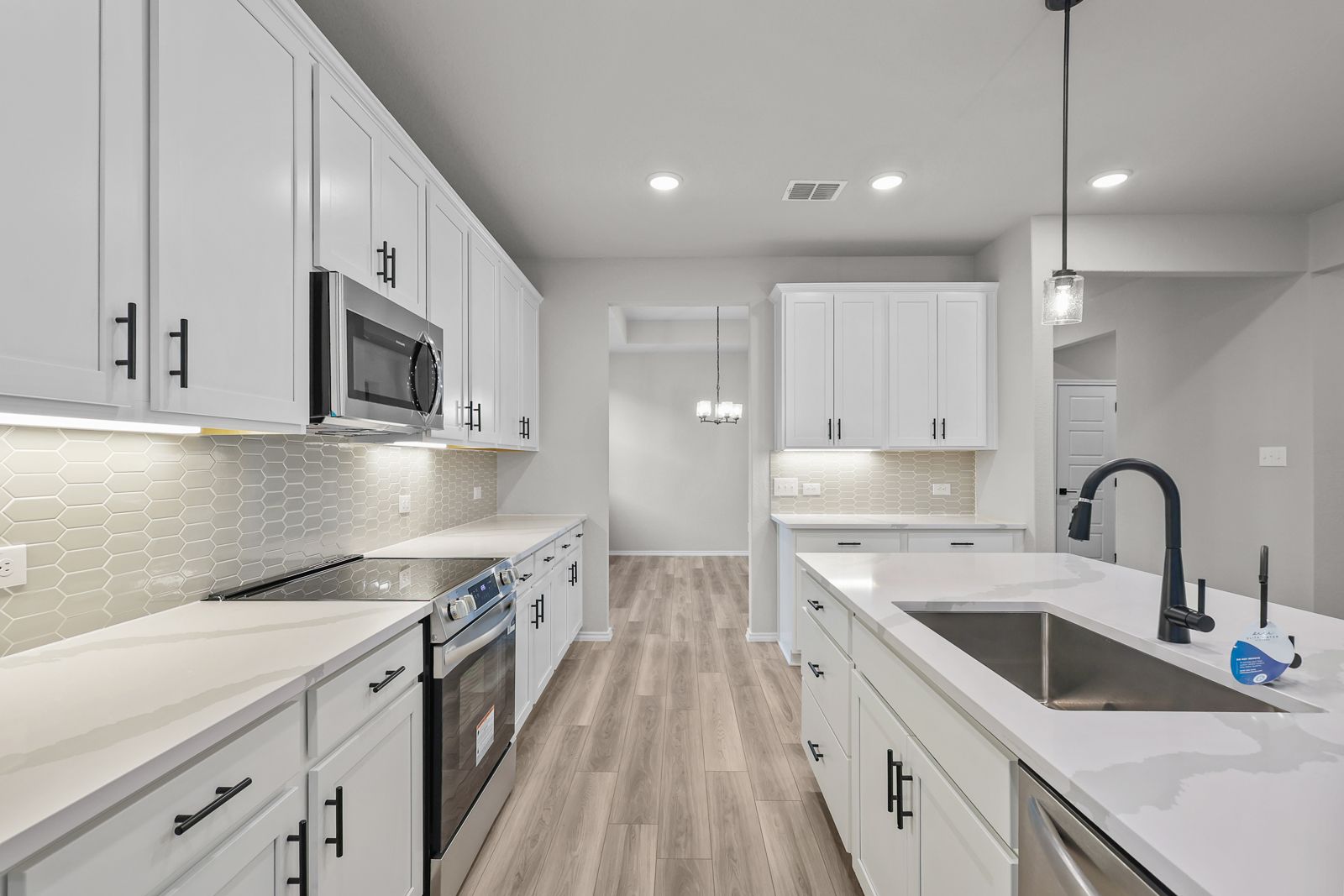 Modern kitchen in The Glenwood featuring white shaker cabinets, quartz countertops, and a central island in Seguin, Texas.