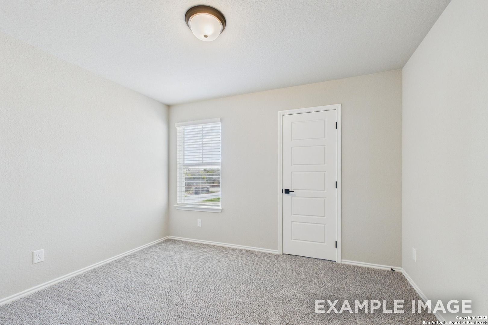 Empty bedroom with beige walls, gray carpet, window blinds, and white door in Davidson Homes The Charlotte A, San Antonio, Texas