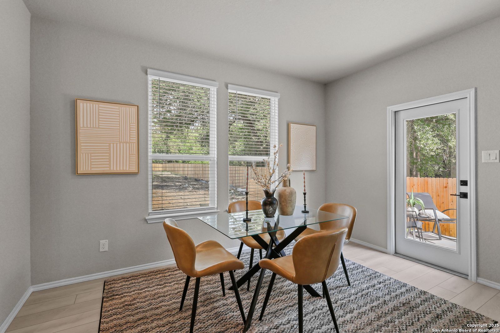 Modern dining room with glass table, leather chairs, and backyard view in Davidson Homes The Charlotte B, San Antonio