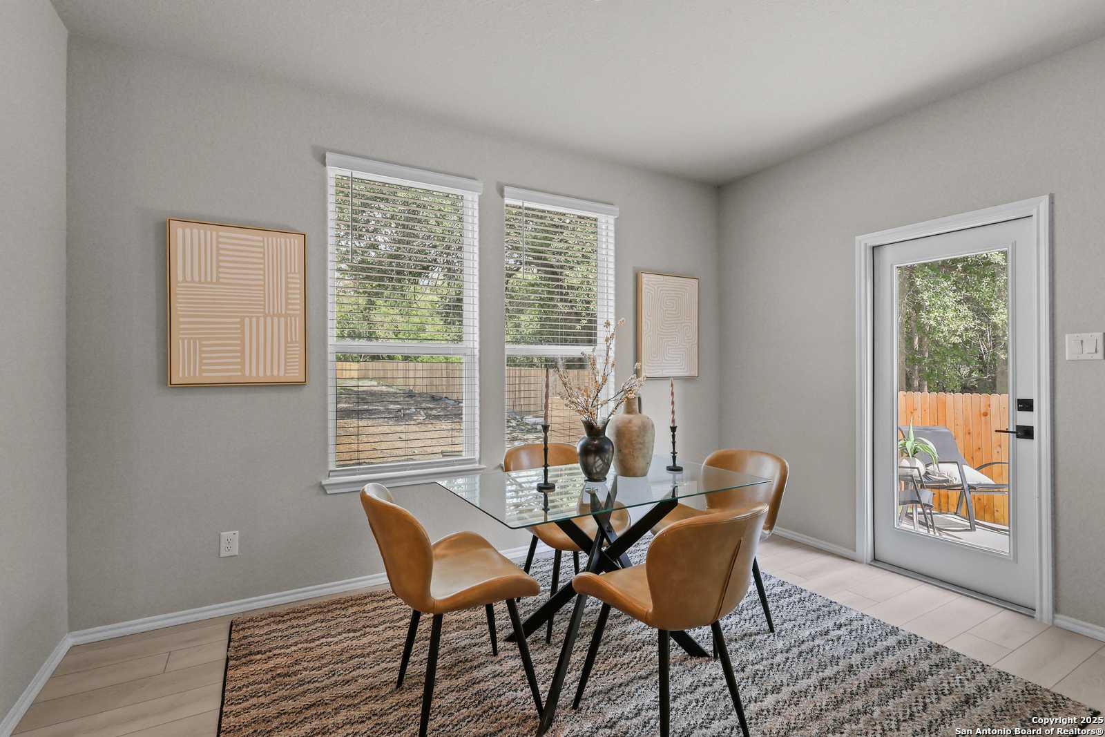 Modern dining room with glass table, leather chairs, and backyard view in Davidson Homes The Charlotte B, San Antonio