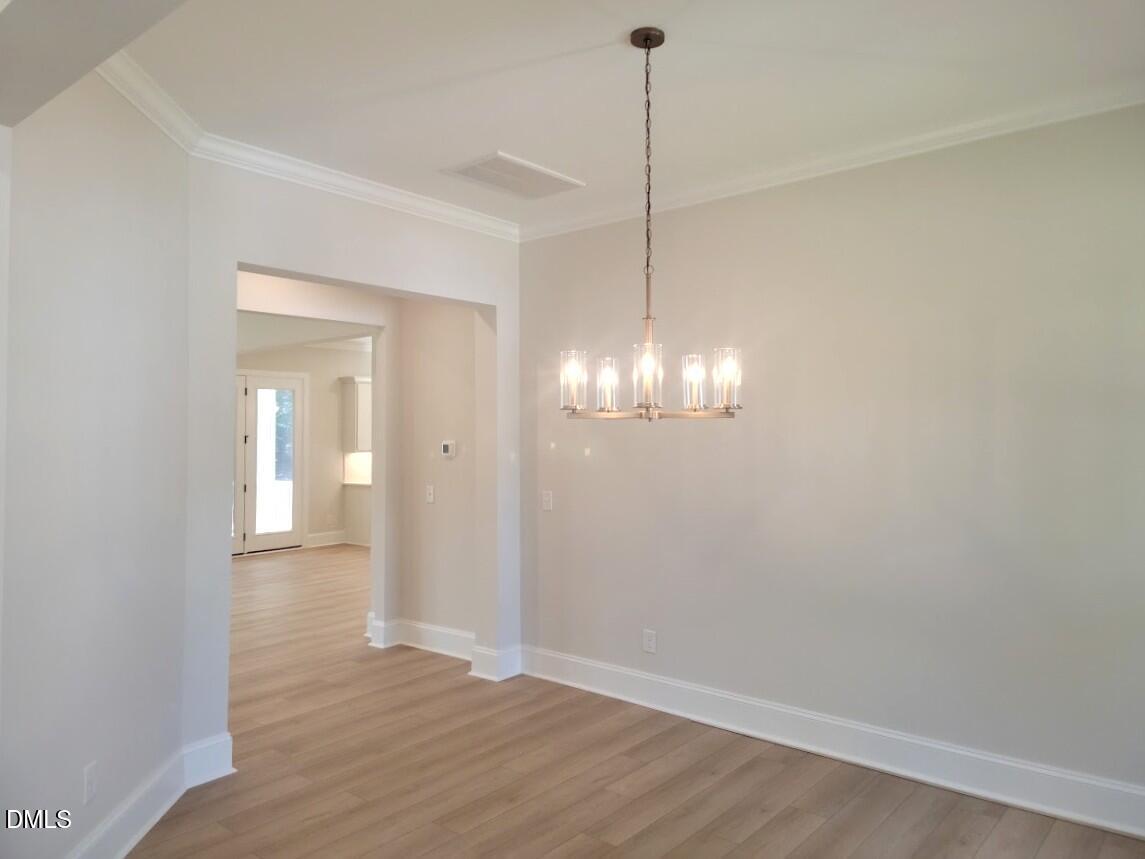 Bright formal dining room with modern chandelier and hardwood floors in Davidson Homes Crawford D plan, Wake Forest, NC