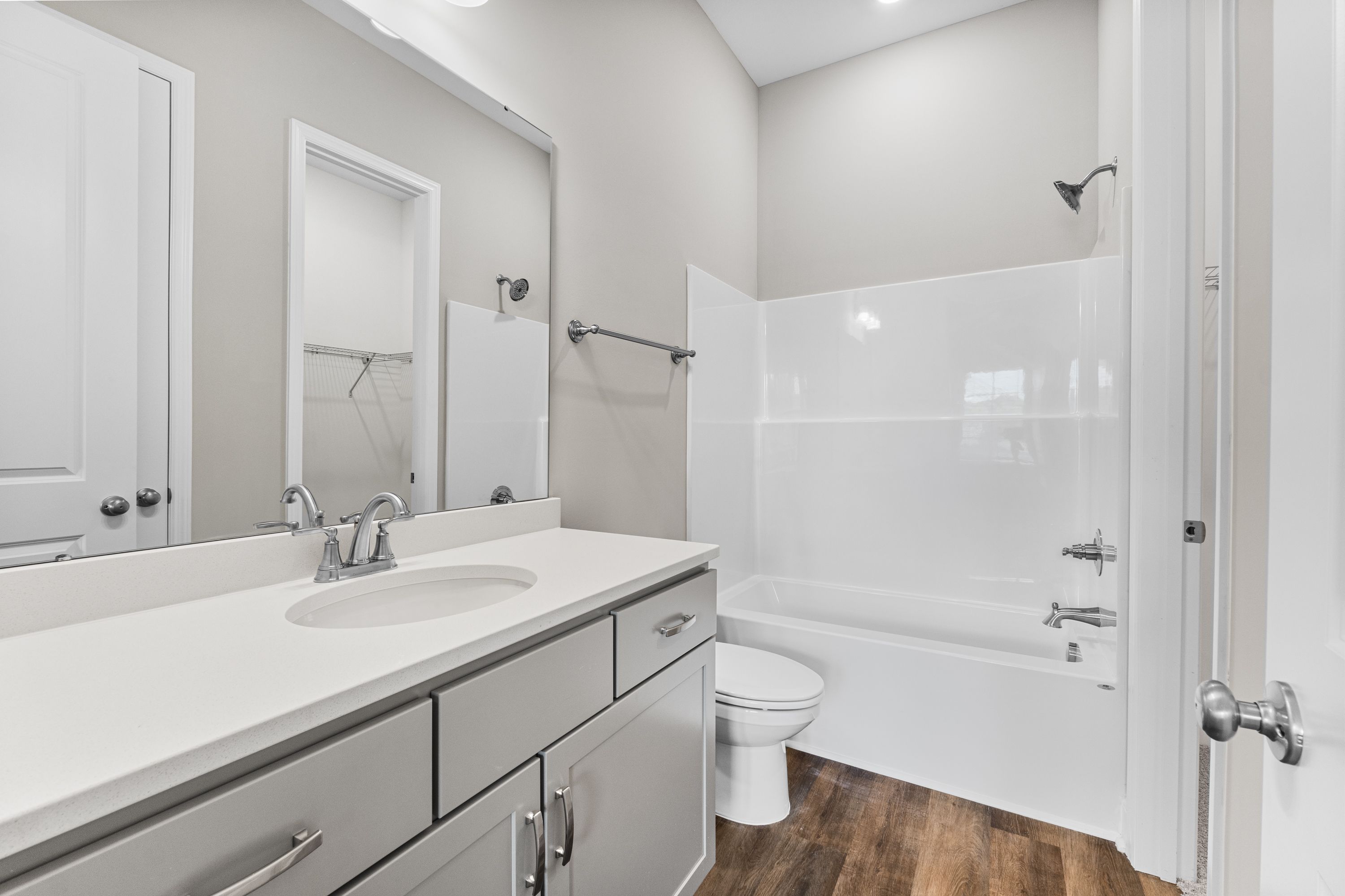 Spacious master bathroom in The Arcadia E with double vanity, white tub-shower combo, and modern gray finishes