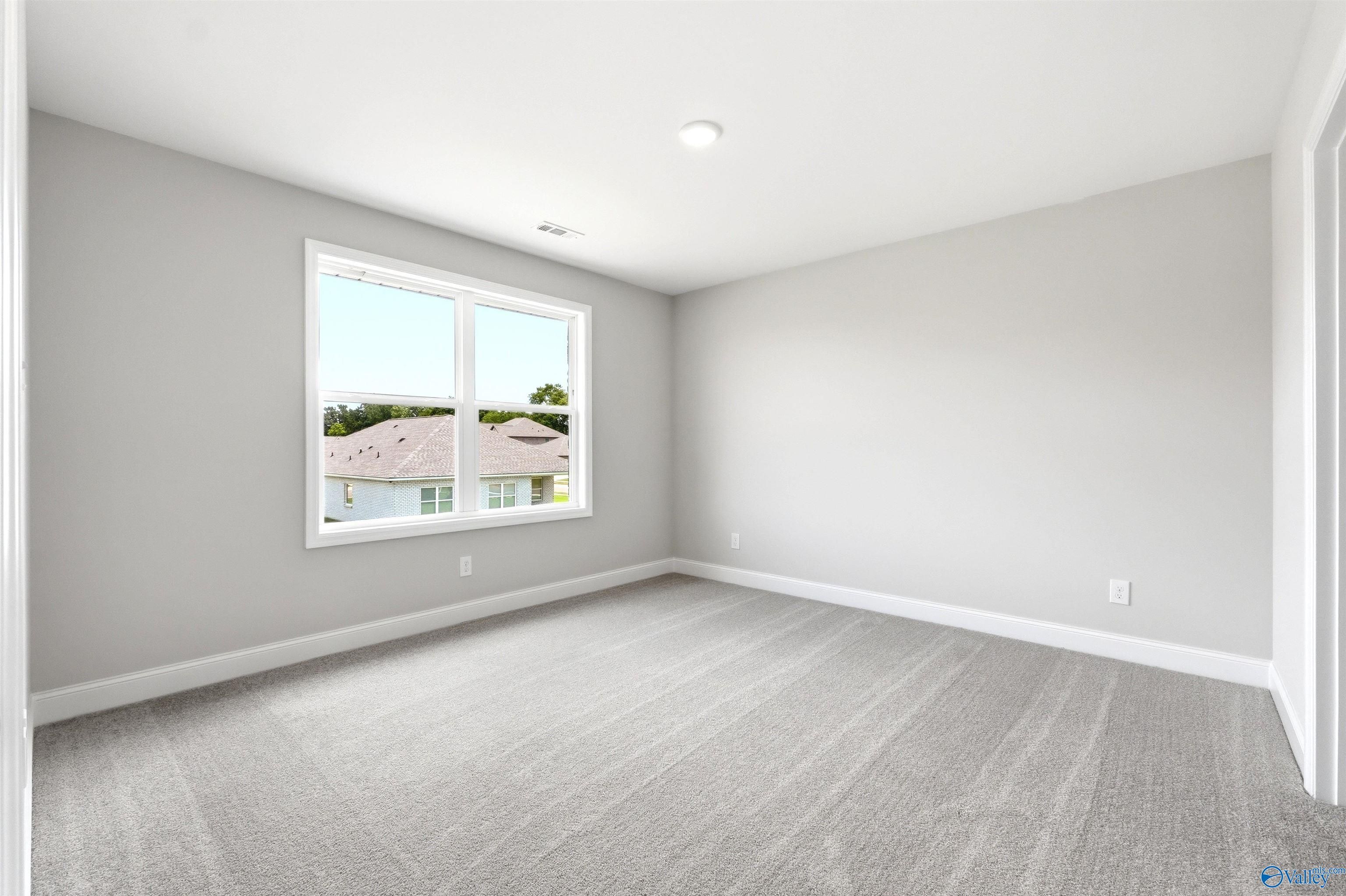 Spacious secondary bedroom with neutral gray walls and plush carpeting in The Shelby A floor plan, Wood Trail, Toney, AL.