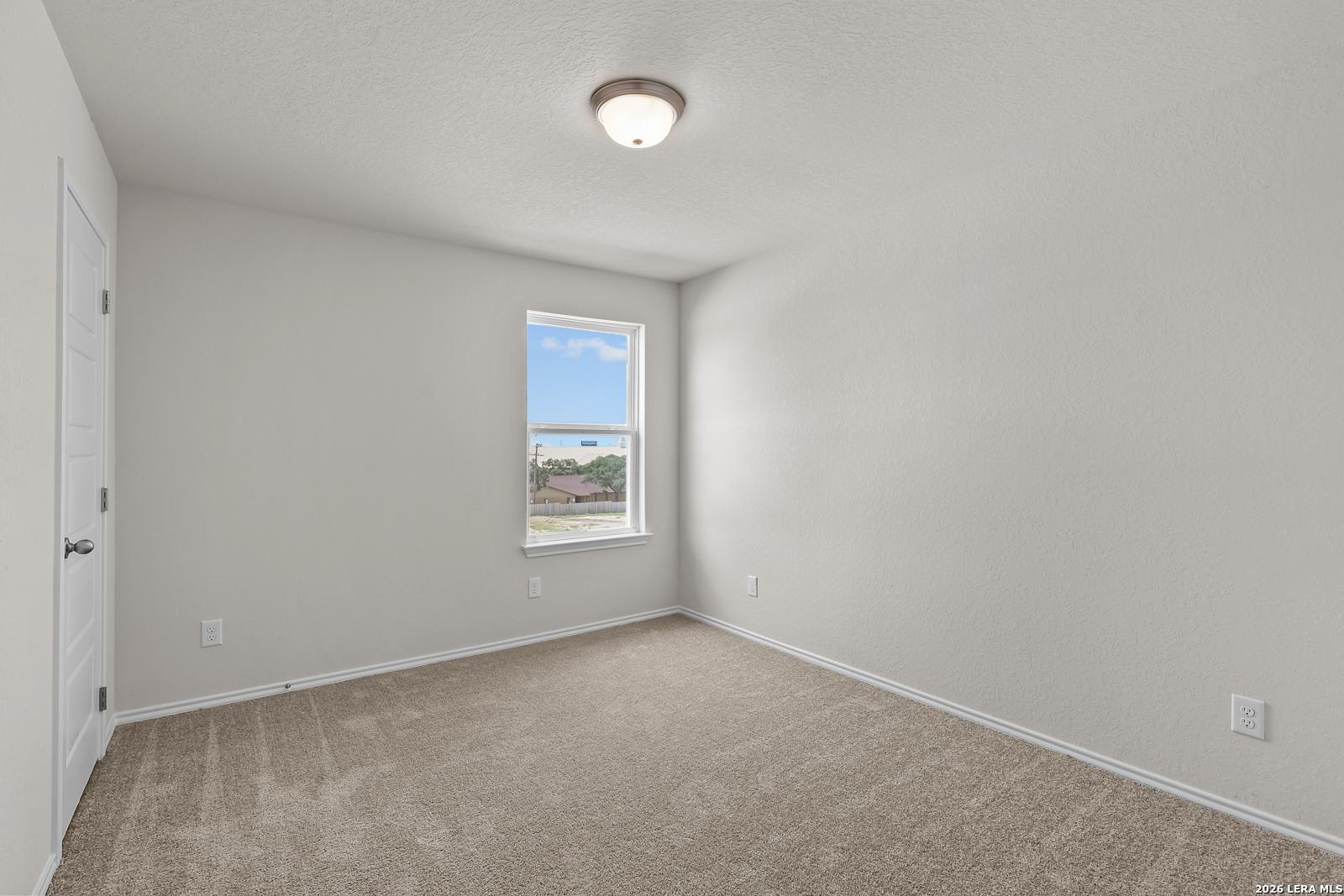 Bright secondary bedroom with neutral walls and plush carpet in The Gillian B floor plan at Meadows at Oak Creek, San Antonio.