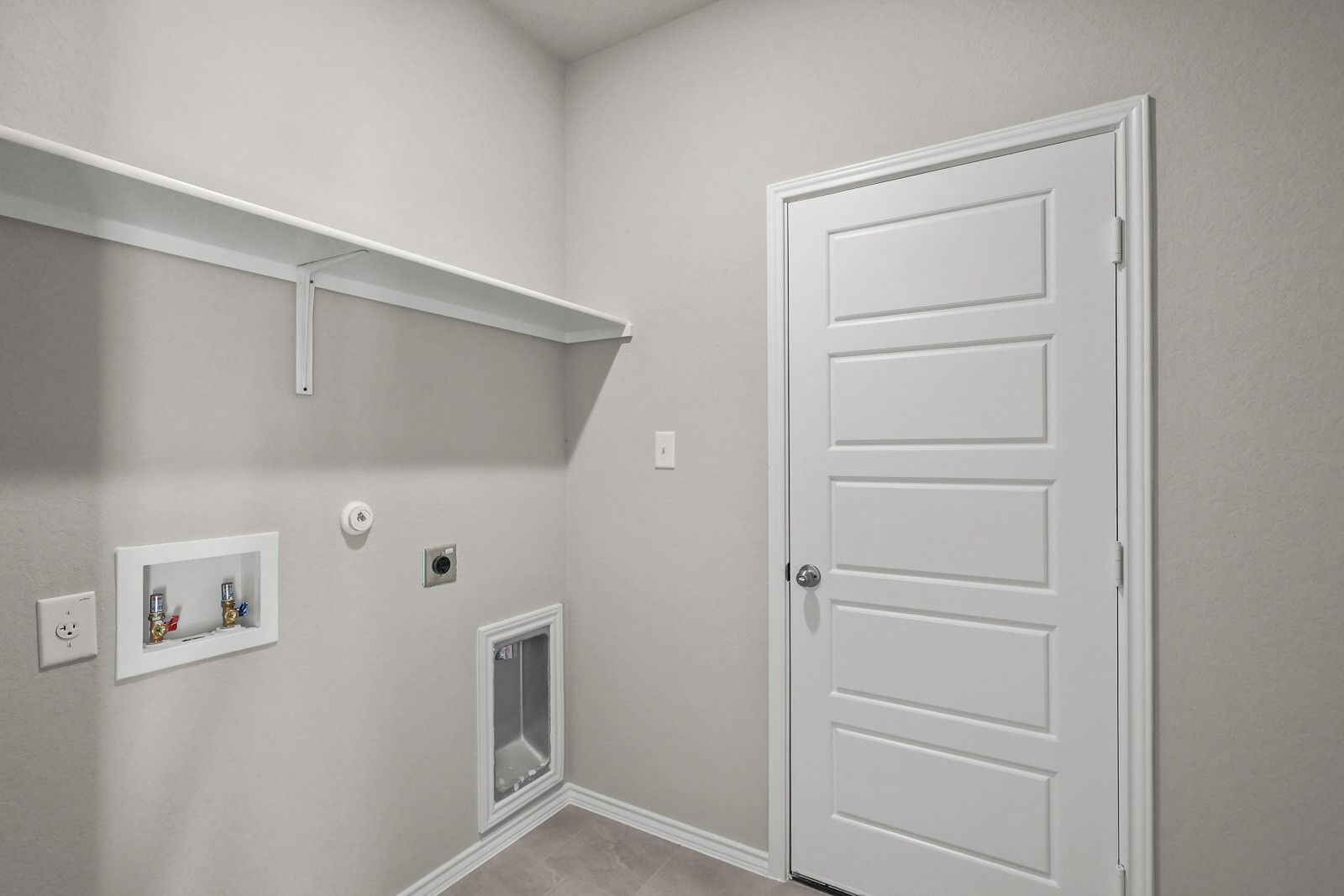 Laundry room with utility connections and built-in shelving in The Frio G floor plan by Davidson Homes in Heartland, TX.