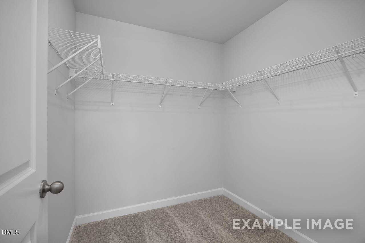 Spacious walk-in closet with white wire shelving and carpeted floor in Davidson Homes The Warren Interior, Fuquay-Varina, NC