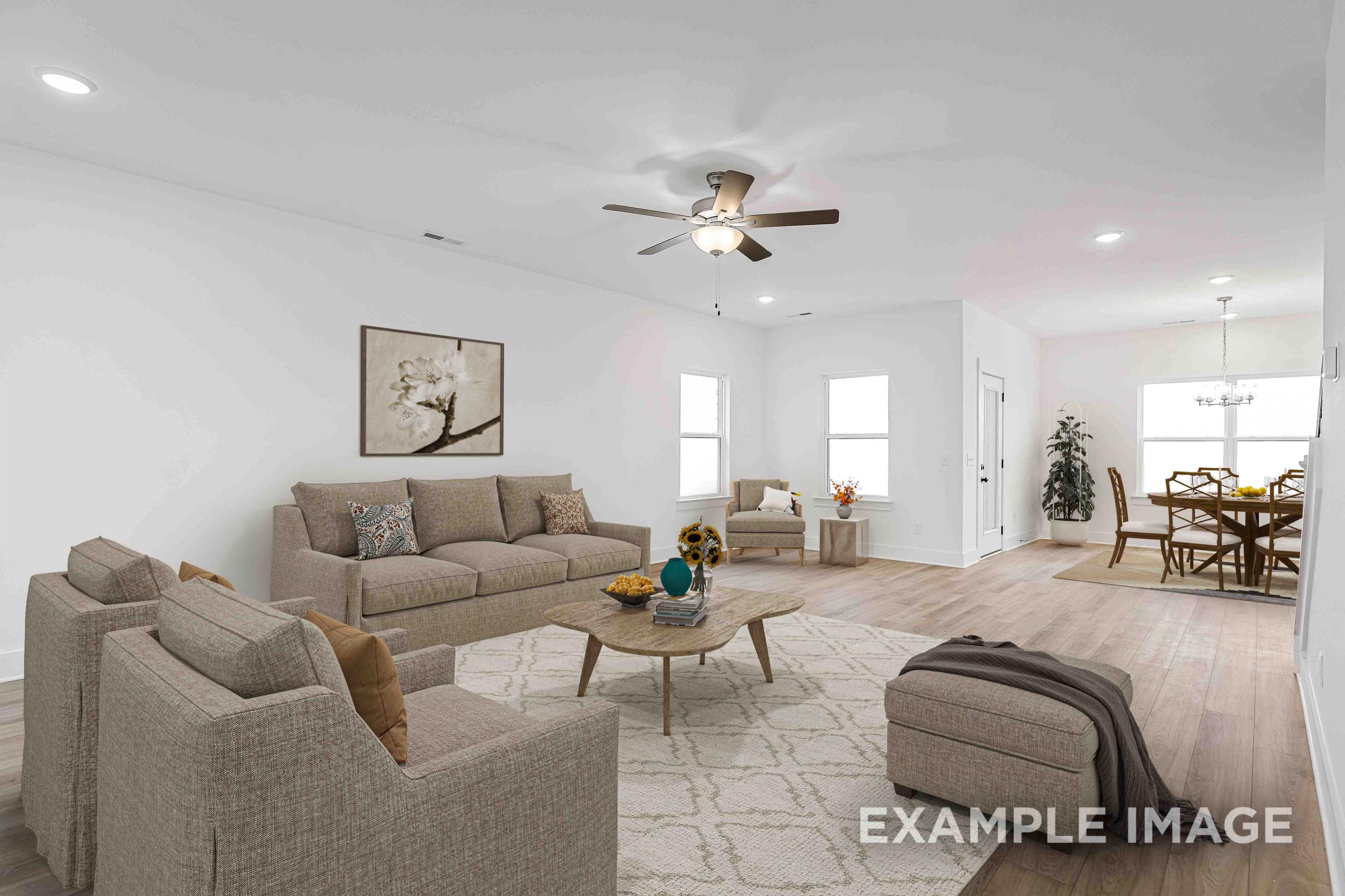 Spacious open-concept living room in The Charleston with beige sofa, armchairs, coffee table, and adjacent dining area