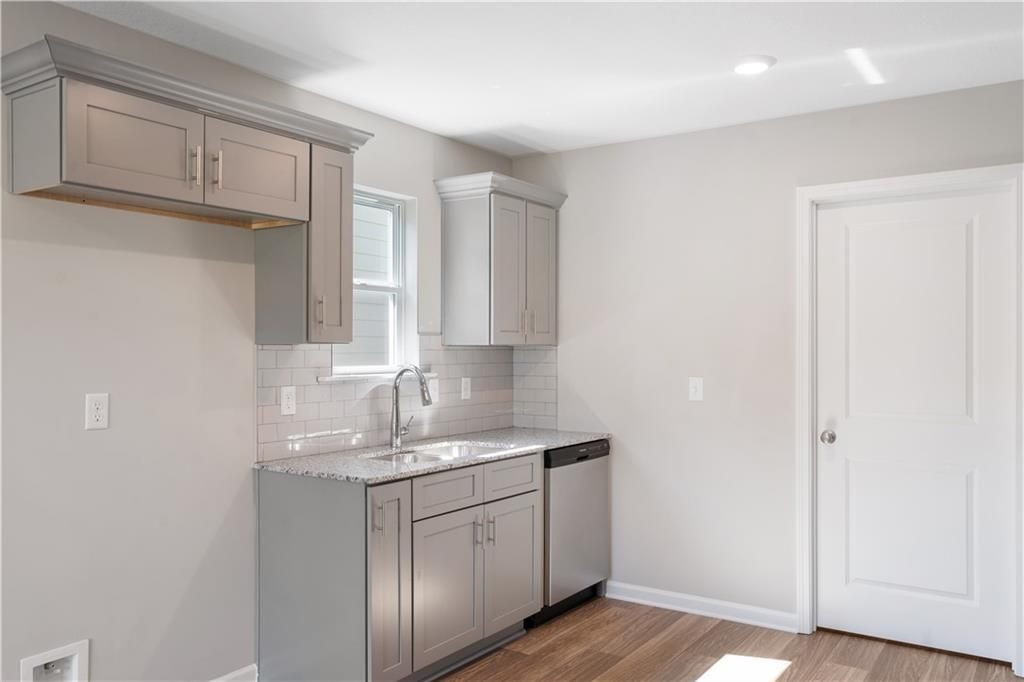 Modern kitchen with gray cabinets, granite countertops, and subway tile backsplash in The Washington plan, Phenix City.