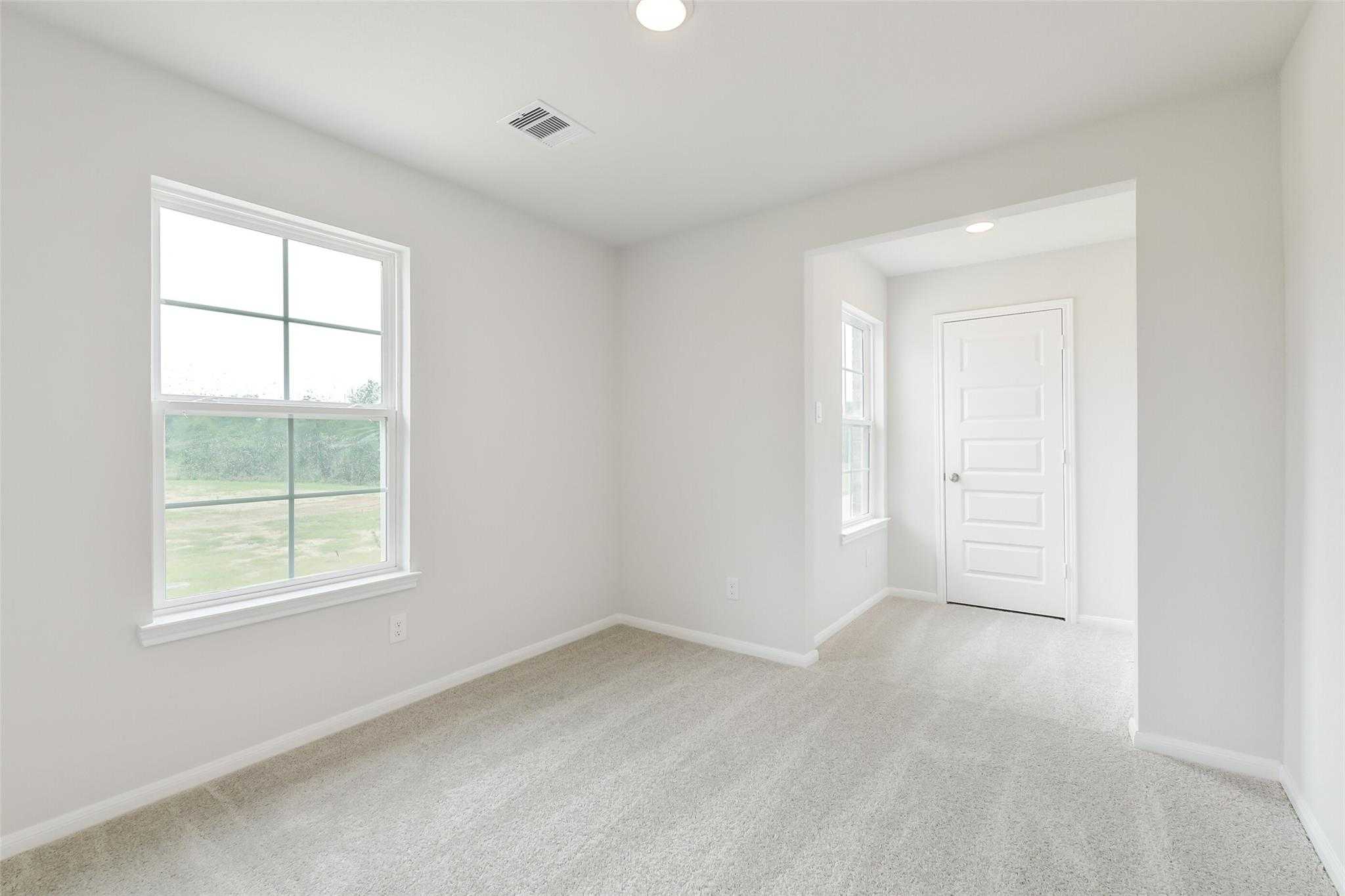 Bright secondary bedroom with large window and neutral carpet in Davidson Homes The Brazos F, Conroe, Texas