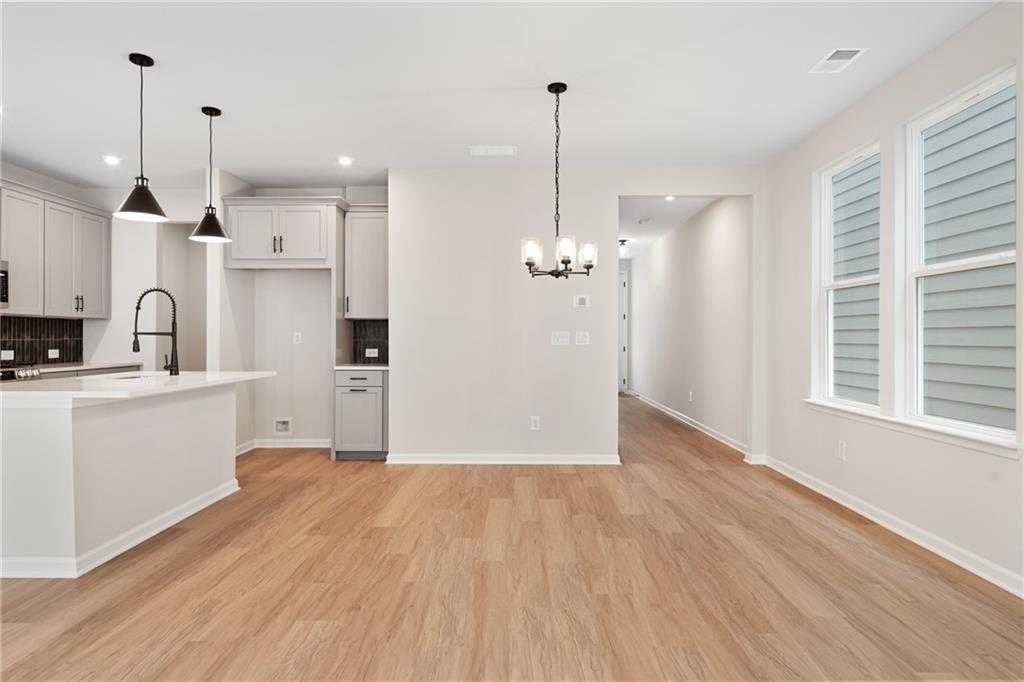 Bright open-concept kitchen with white cabinets, large island sink, pendant lights, and hardwood floors in Davidson Homes The Marion A, Kennesaw, GA