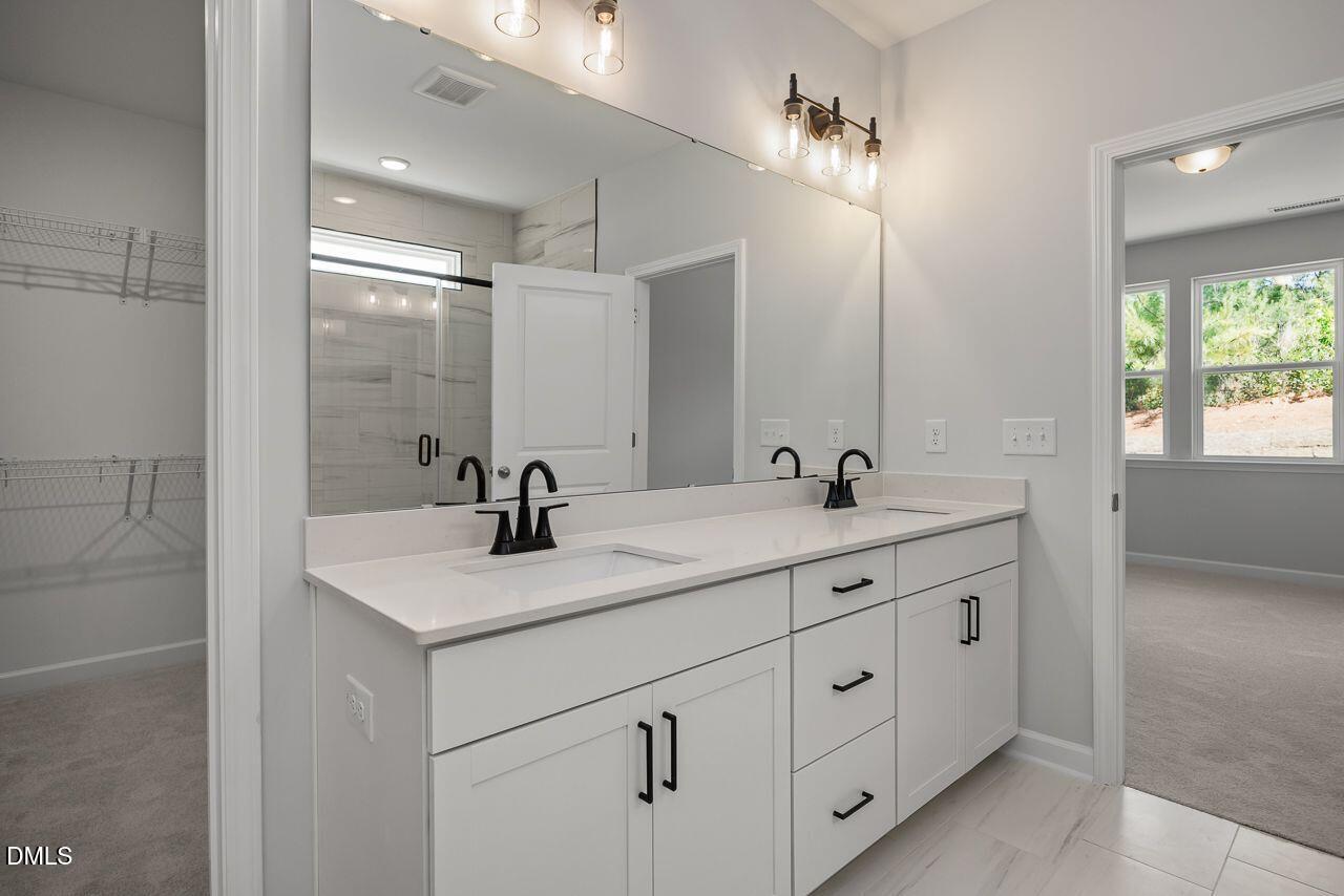 Modern bathroom vanity with double sinks and matte black fixtures in Davidson Homes The Birch II A in Aberdeen, NC.