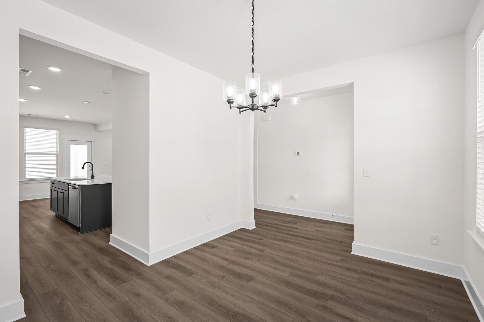 Bright dining area with modern chandelier and wood-look flooring in The Willow floor plan at Woods Crossing, Gallatin, TN.