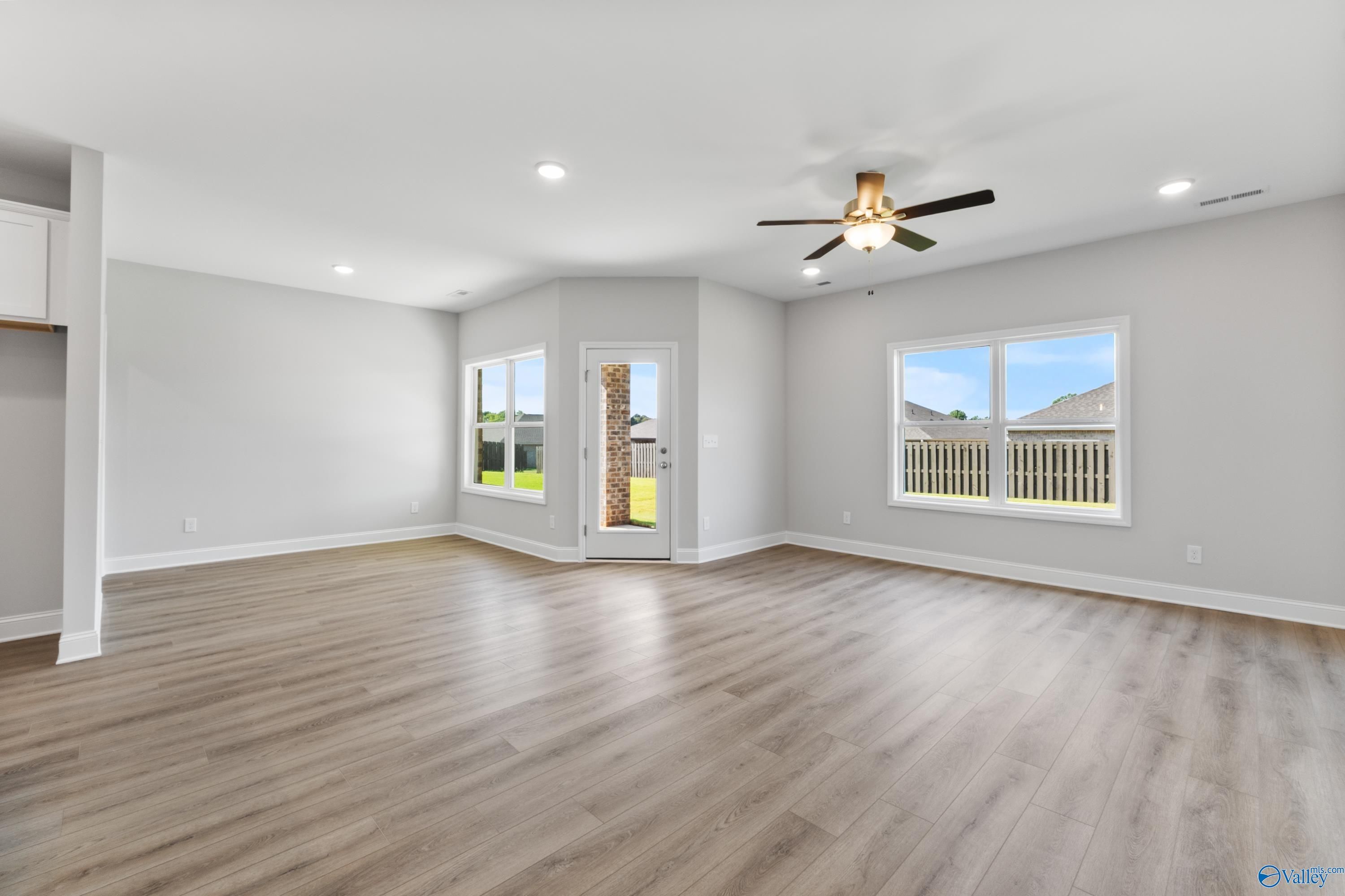 Spacious living room with hardwood floors, ceiling fan, and French doors to backyard in Davidson Homes The Daphne, Hazel Green, AL
