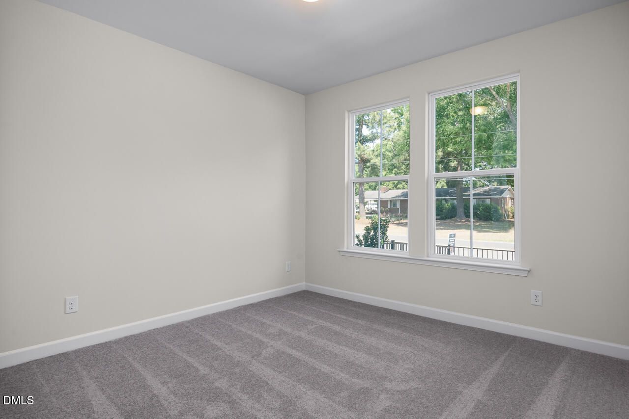 Bright, carpeted bedroom with neutral walls in The Mitchell floor plan by Davidson Homes in Camden Park, Knightdale, NC.