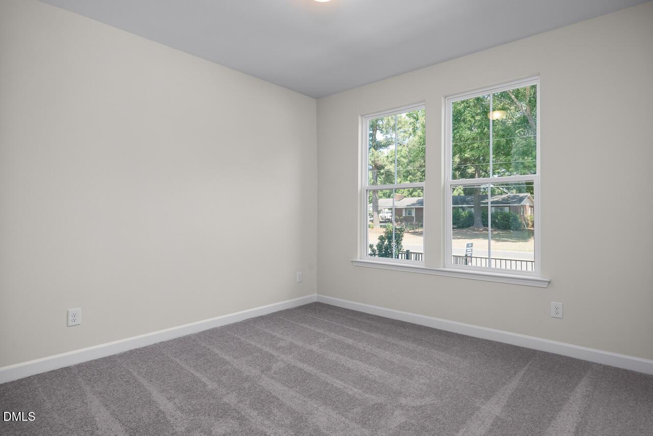 Bright, carpeted bedroom with neutral walls in The Mitchell floor plan by Davidson Homes in Camden Park, Knightdale, NC.