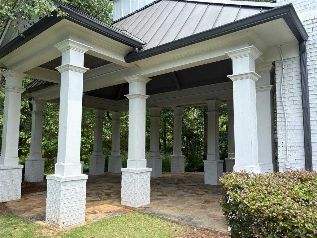 Elegant covered front porch with white columns and metal roof on white brick 5-bedroom Davidson Homes Hickory B in Riverwood, Dallas, Georgia