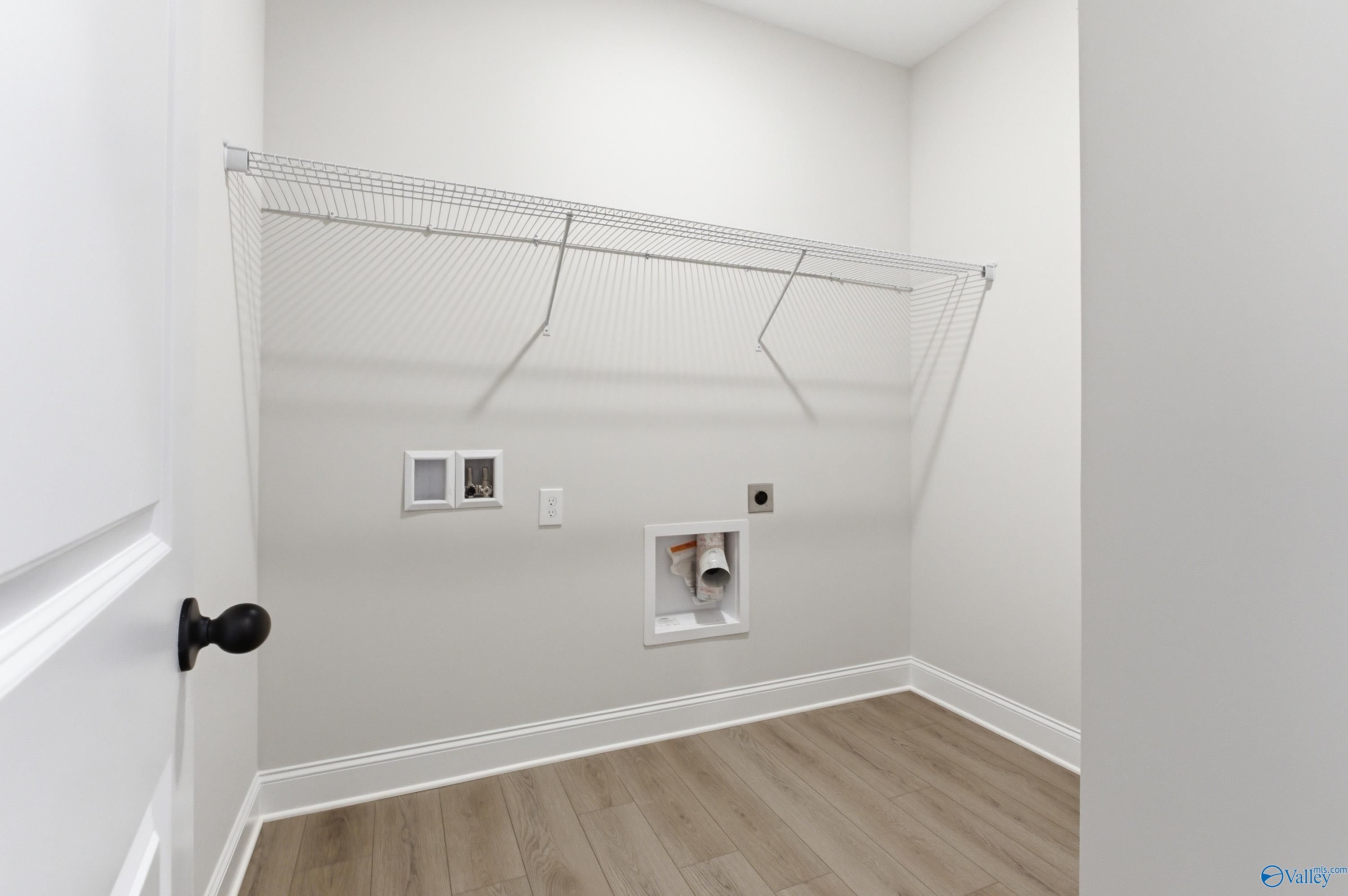 Bright laundry room with wire shelving, washer-dryer hookups, and laminate flooring in Davidson Homes The Daphne C, Huntsville, AL