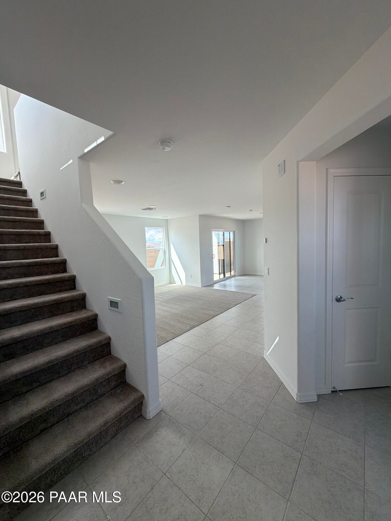 Bright open foyer with carpeted staircase and tile flooring leading to living room in Davidson Homes' Wilmington B, Prescott, AZ