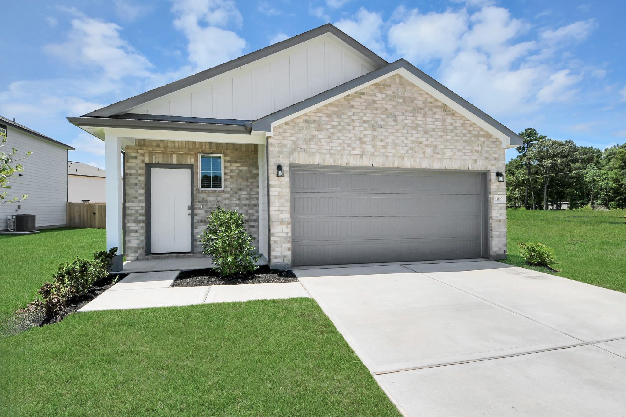 1-story brick and white siding home with 2-car garage at The Frio F floor plan in Liberty Estates, Cleveland, Texas.