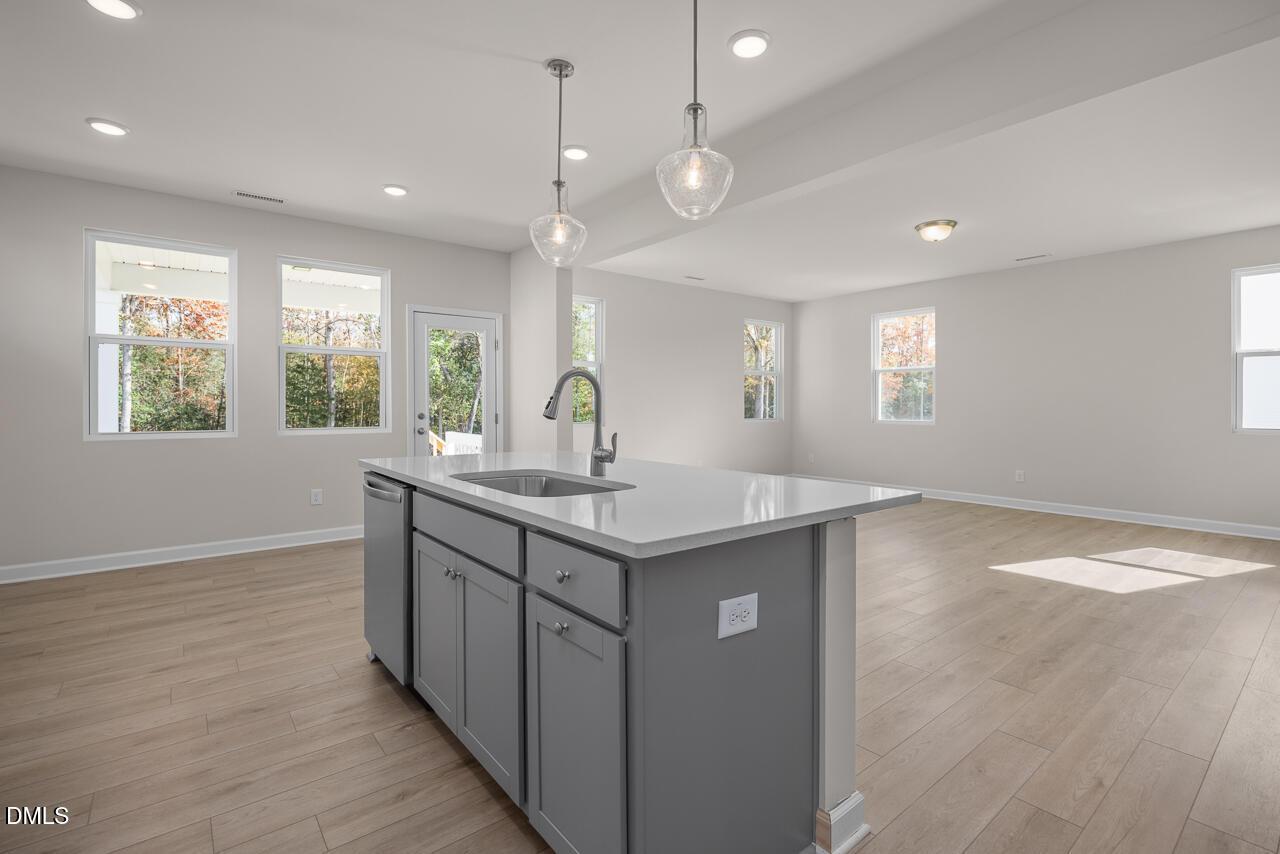 Modern open-concept kitchen with gray island cabinets, white quartz counters, and pendant lights in Davidson Homes Gavin C, Lillington, NC