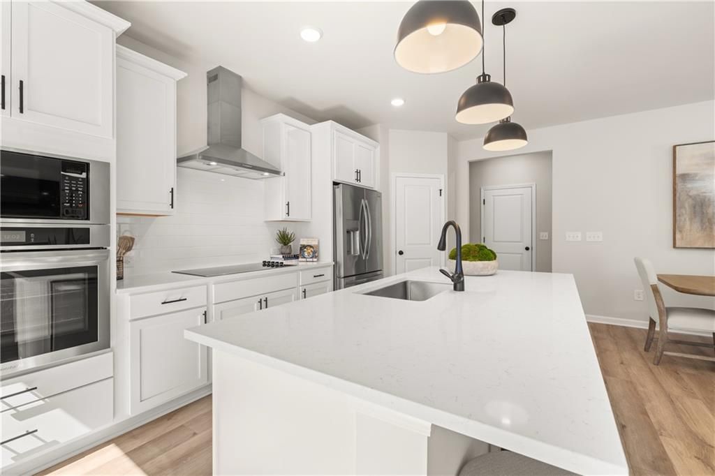 Modern white shaker kitchen with quartz island, stainless appliances, and pendant lights in Davidson Homes The Burton C, Canton, GA